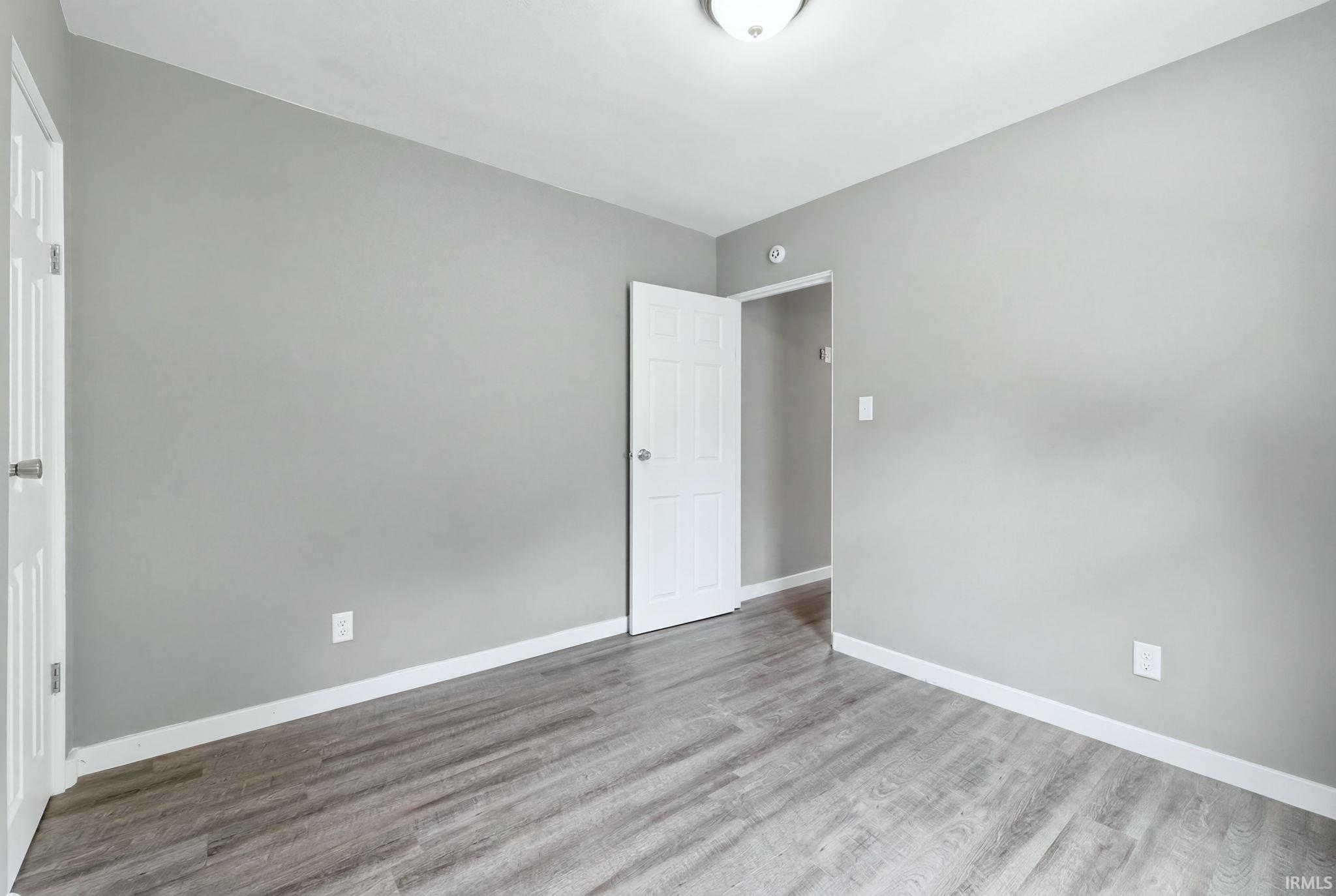 Room featuring wood-finish flooring, light grey painted walls, white trim, and a flush mount ceiling light