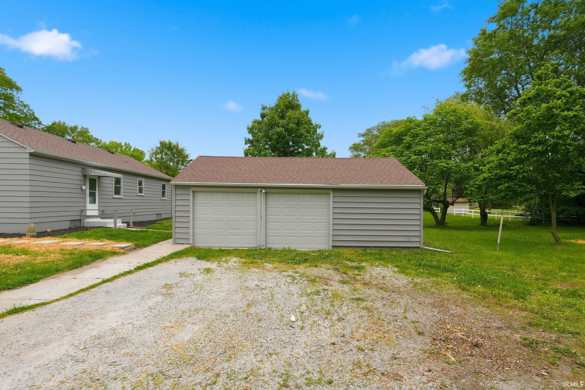 Detached two-car garage with light gray siding and a brown shingle roof