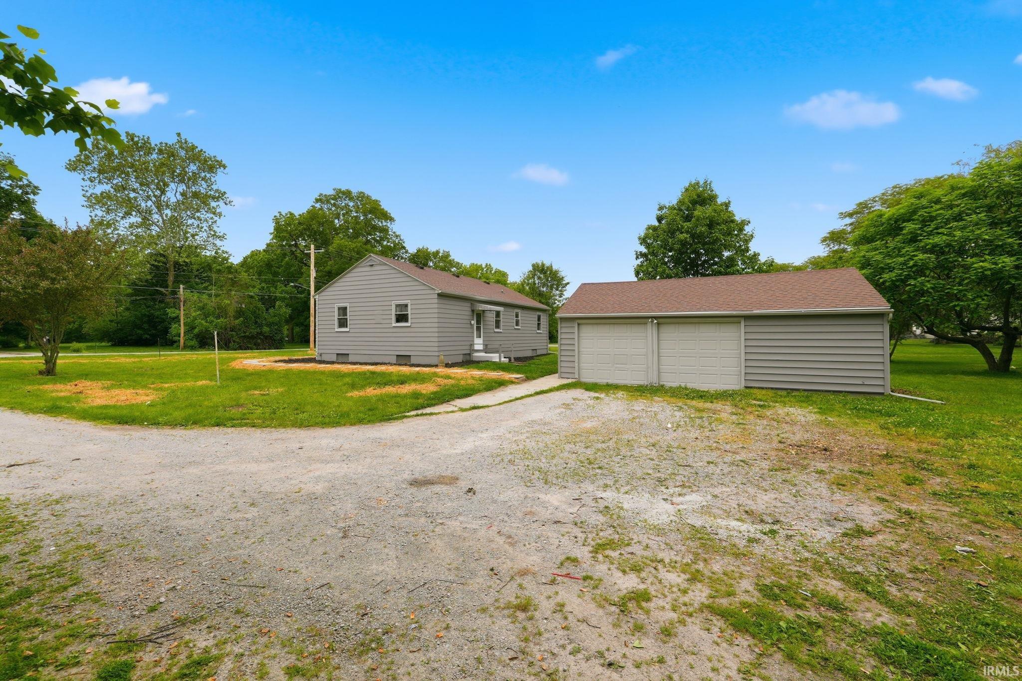 Detached two-car garage with light gray siding and a brown shingle roof