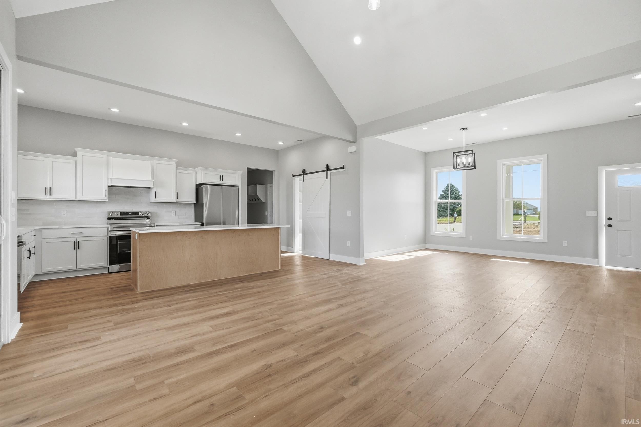 Spacious open-concept interior featuring wood-finish flooring, vaulted ceilings, and recessed lighting