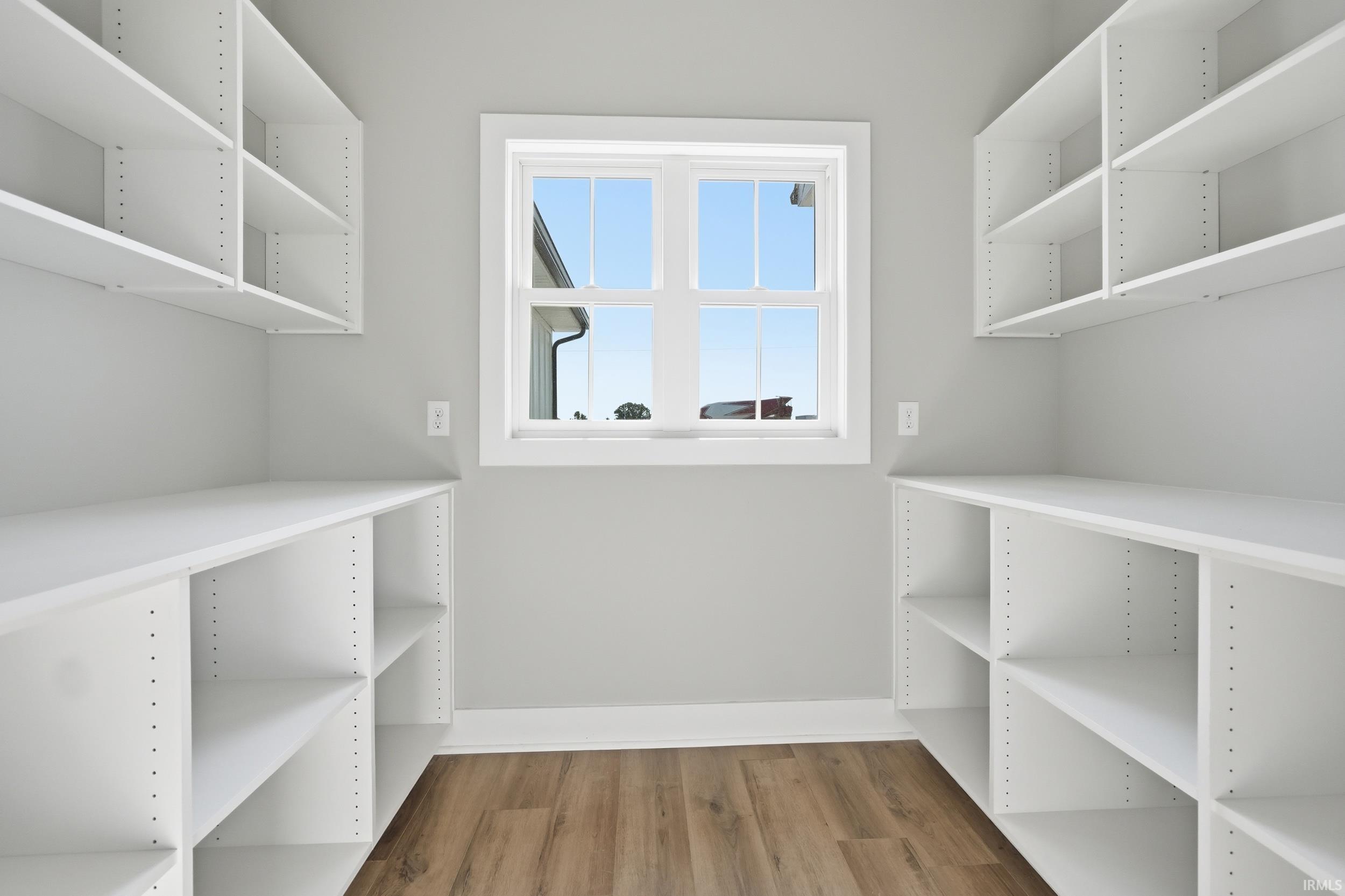 U-shaped pantry featuring extensive white shelving and wood-finish flooring