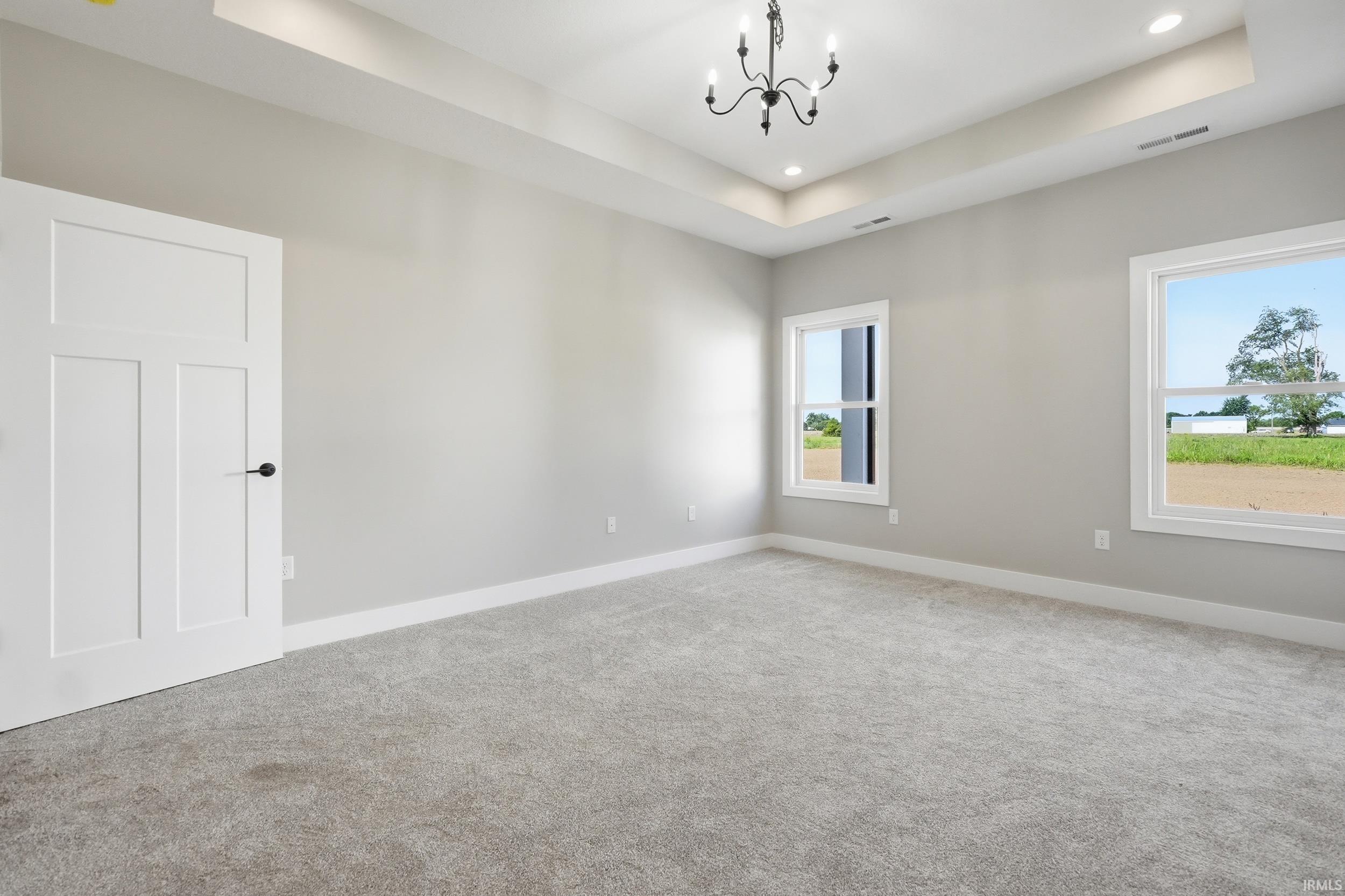 Spacious room featuring light gray walls and plush gray carpeting