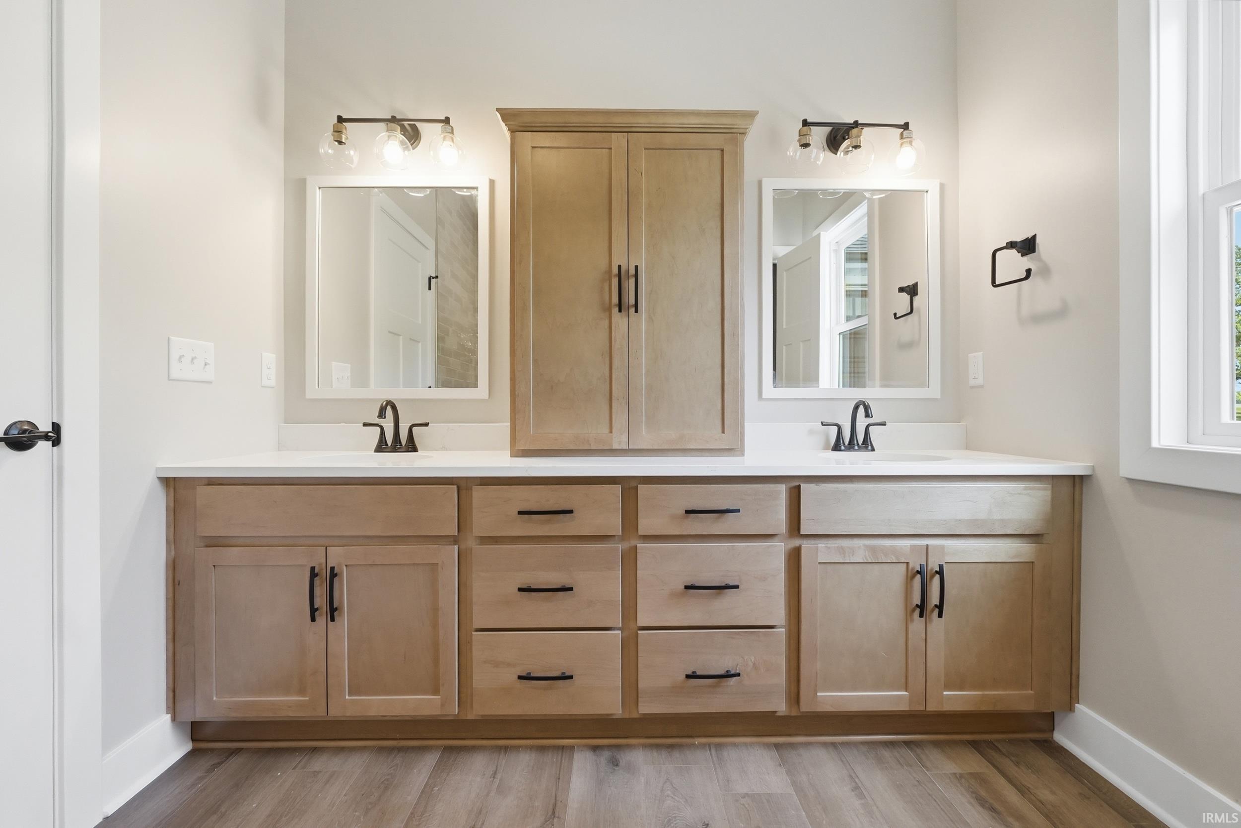 Double vanity featuring light wood cabinetry, white countertops, dual rectangular undermount sinks with matte black faucets, and individual framed mirrors