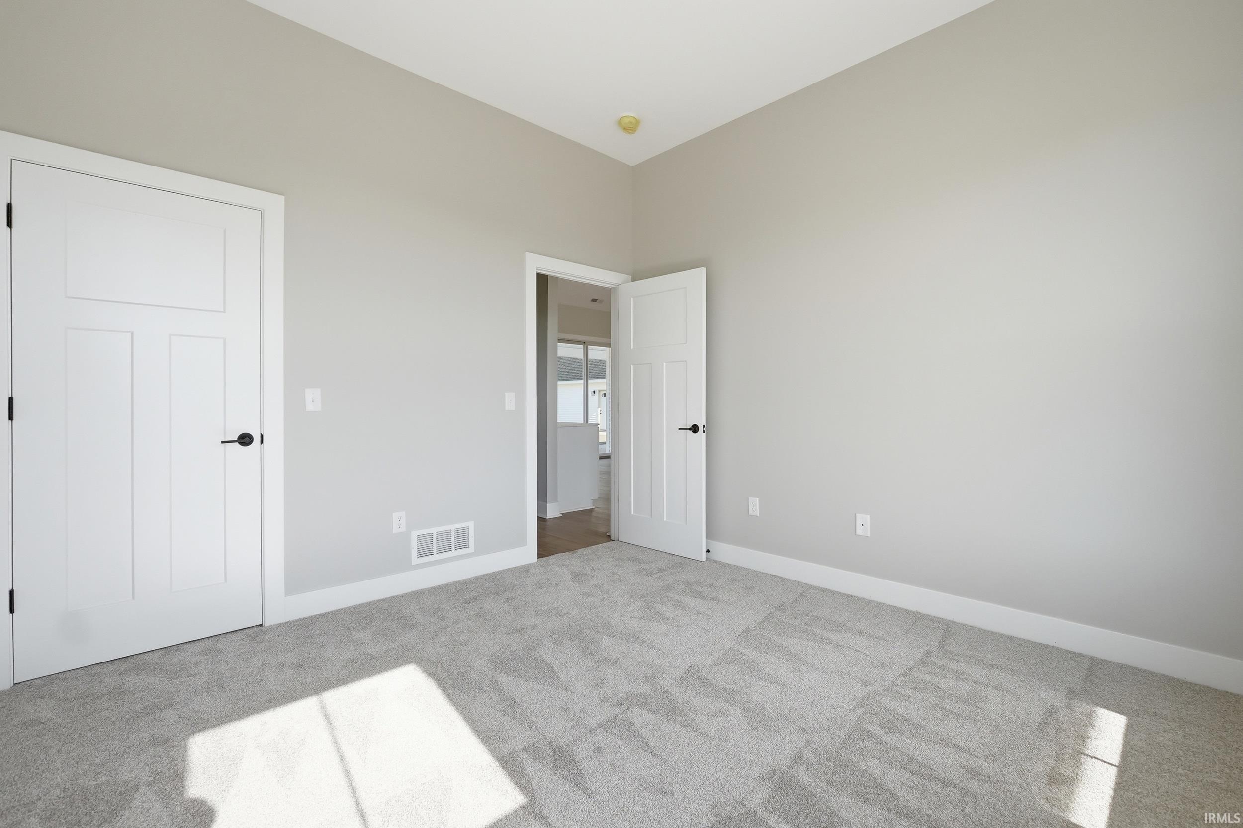 Neutral-toned room featuring light gray walls, plush gray carpeting, and white baseboards