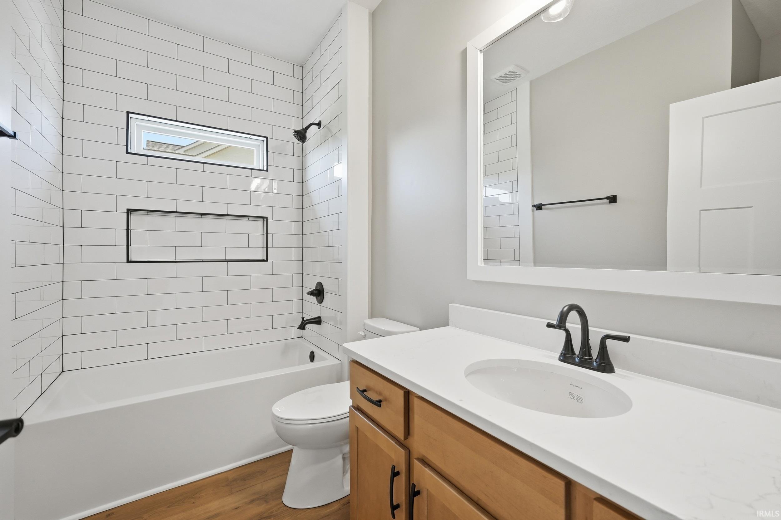 Bathroom featuring a white subway tile shower surround with integrated niche, horizontal window, and matte black fixtures