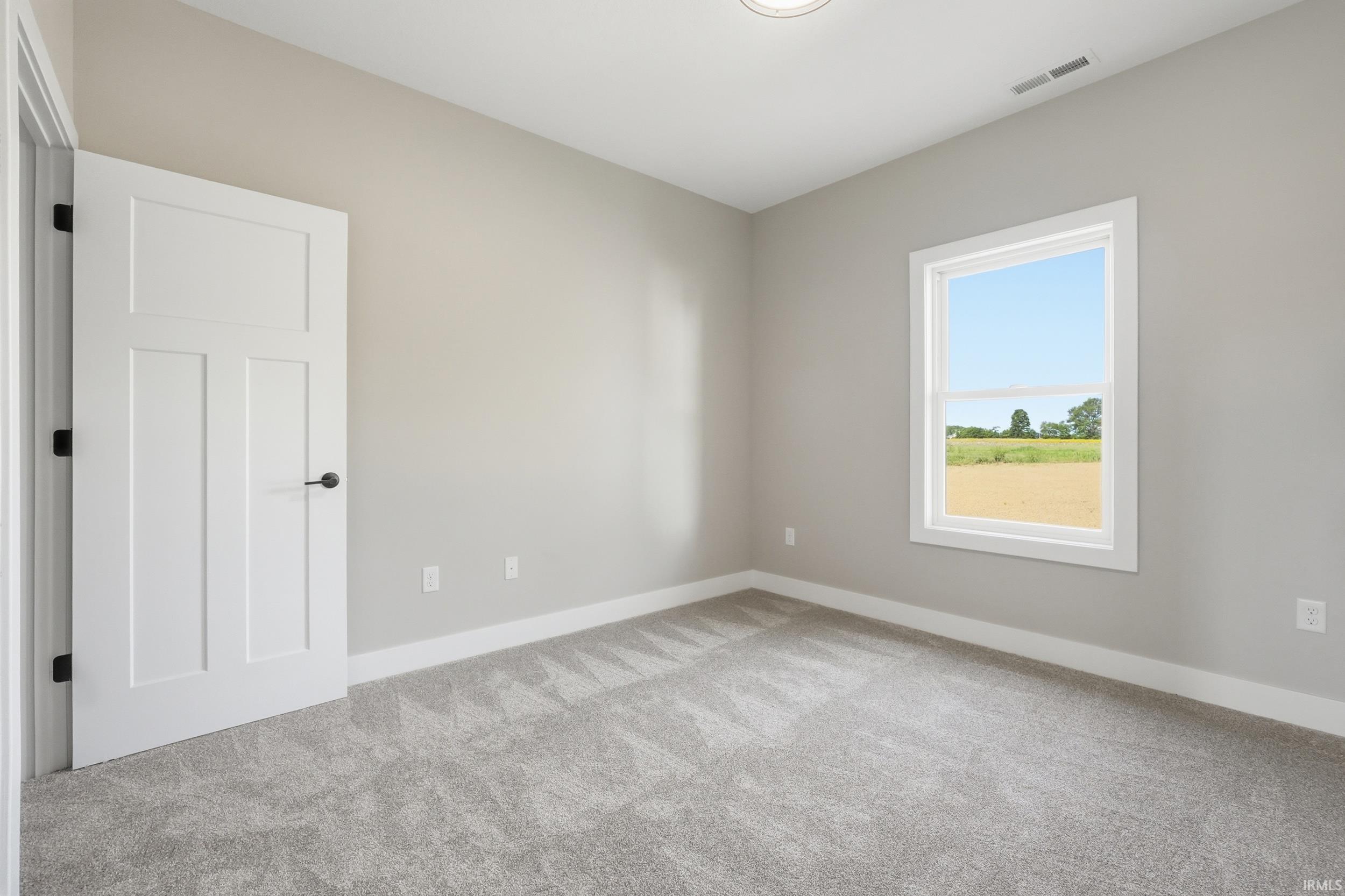 Light gray carpeted room featuring a white single-hung window with a field backdrop