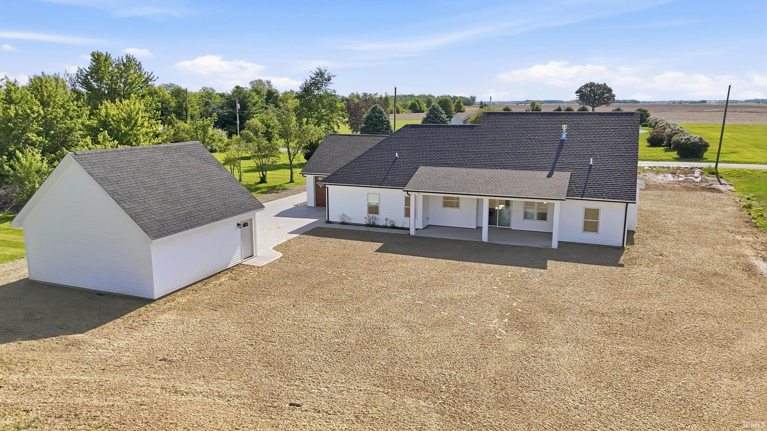 White exterior residence with a covered patio and attached garage, complemented by a detached garage structure