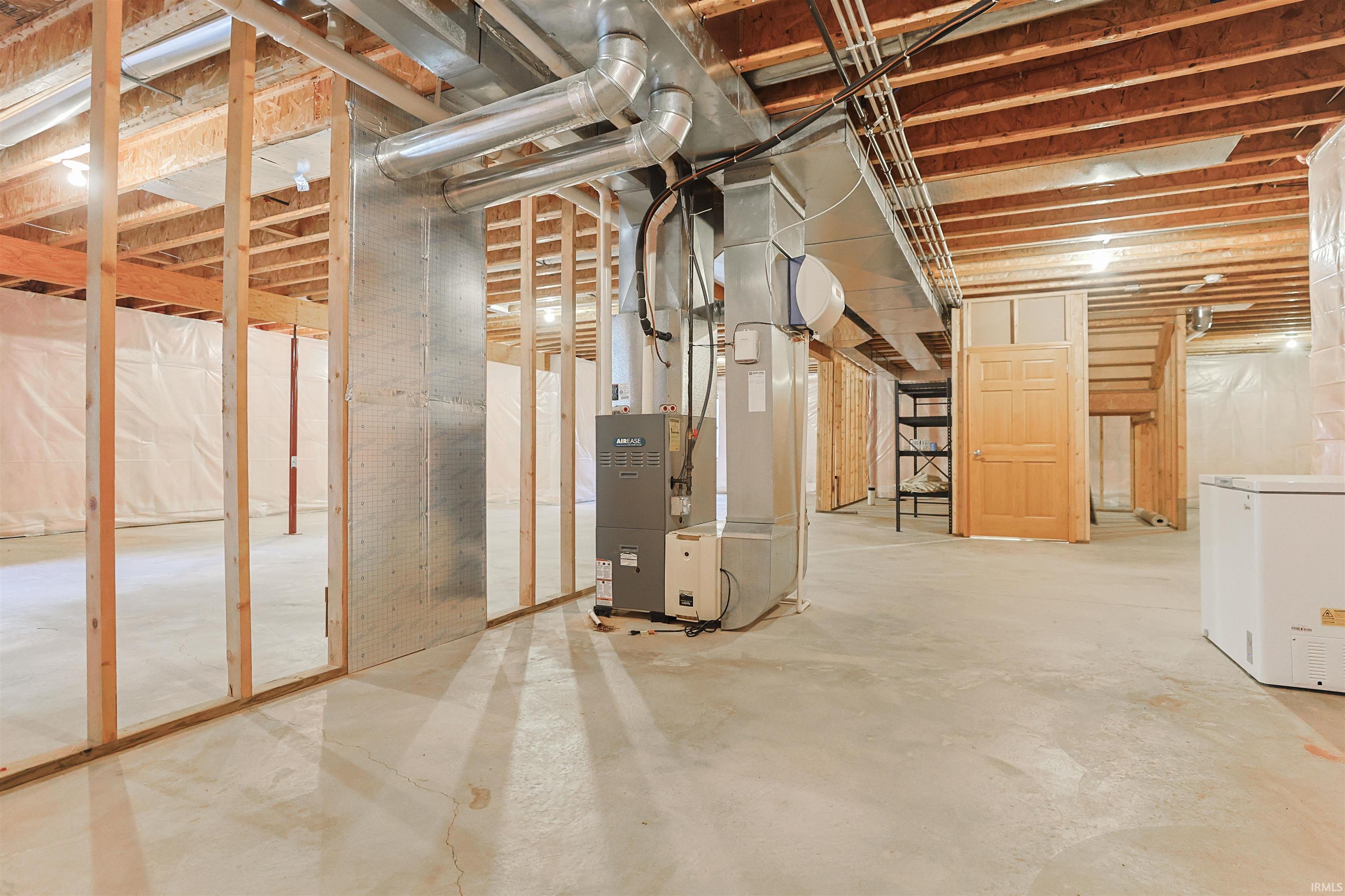 Unfinished basement featuring exposed wood framing, concrete flooring, and two egress windows.
