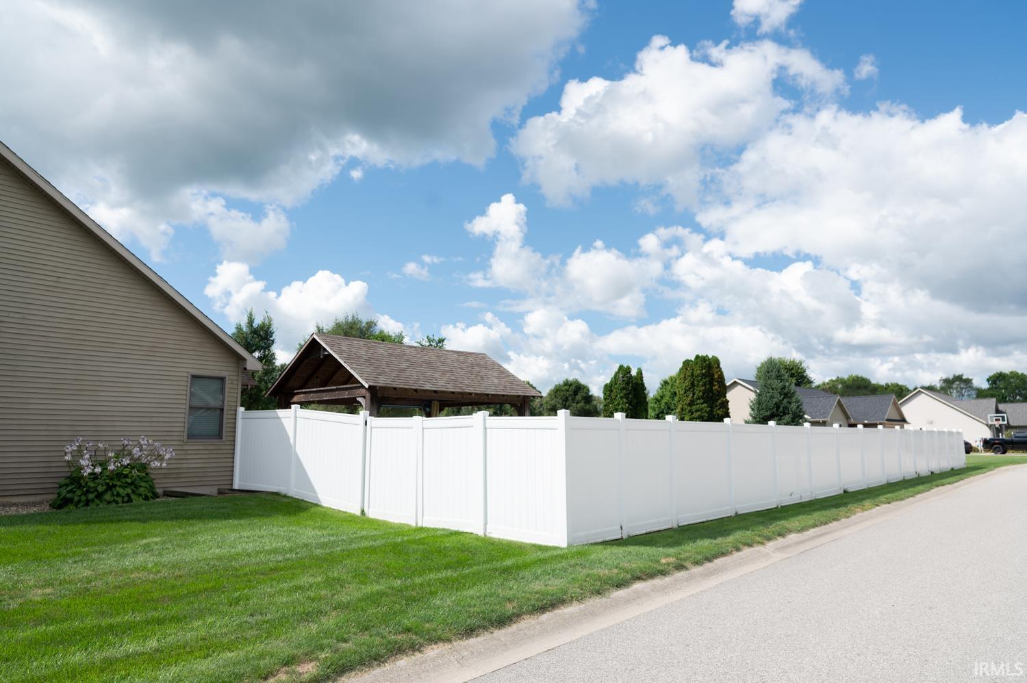 Expansive white vinyl fencing bordering the property, featuring a manicured lawn and a visible side elevation with neutral siding