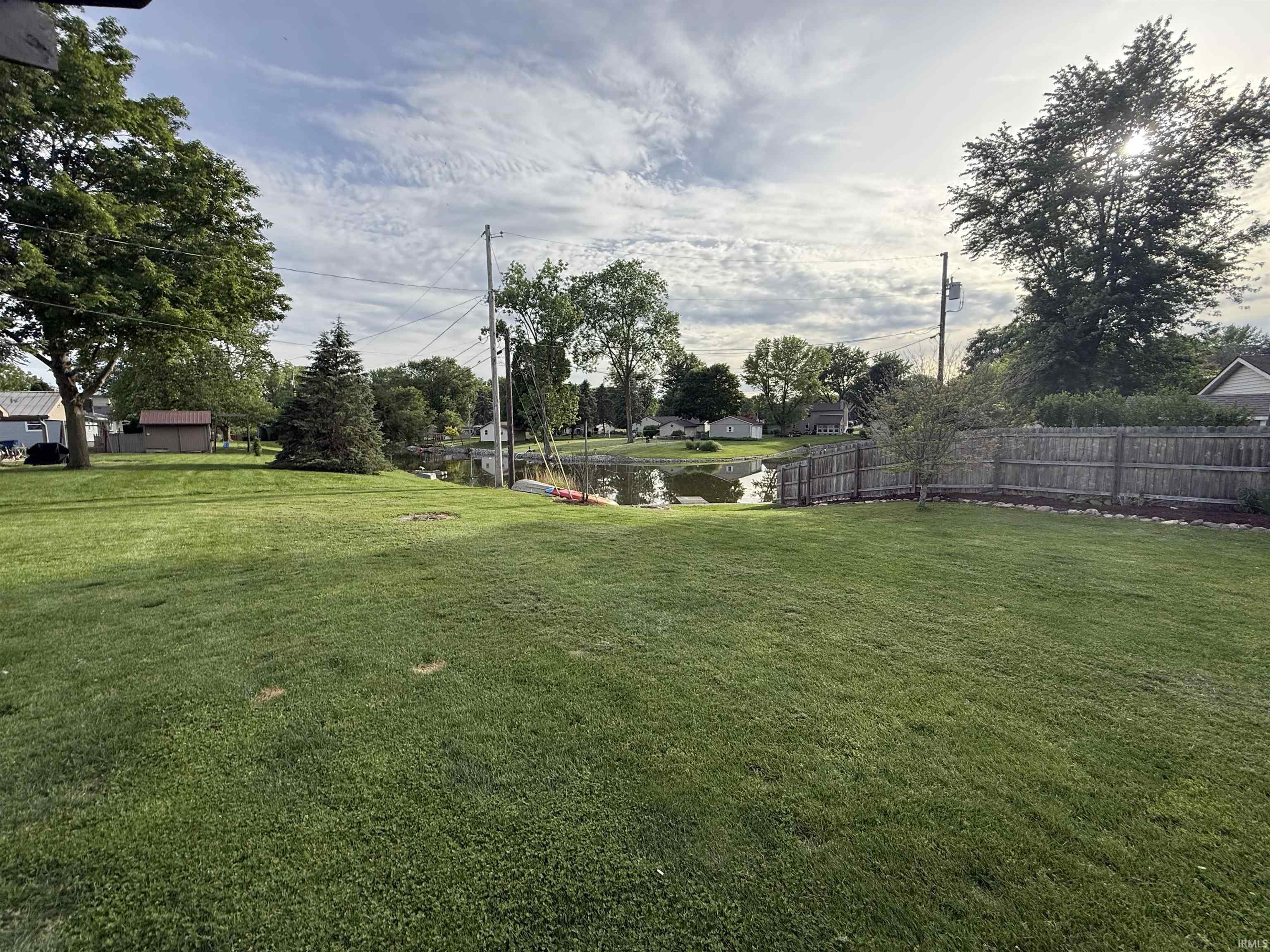 Expansive green lawn with mature trees and a tranquil pond feature