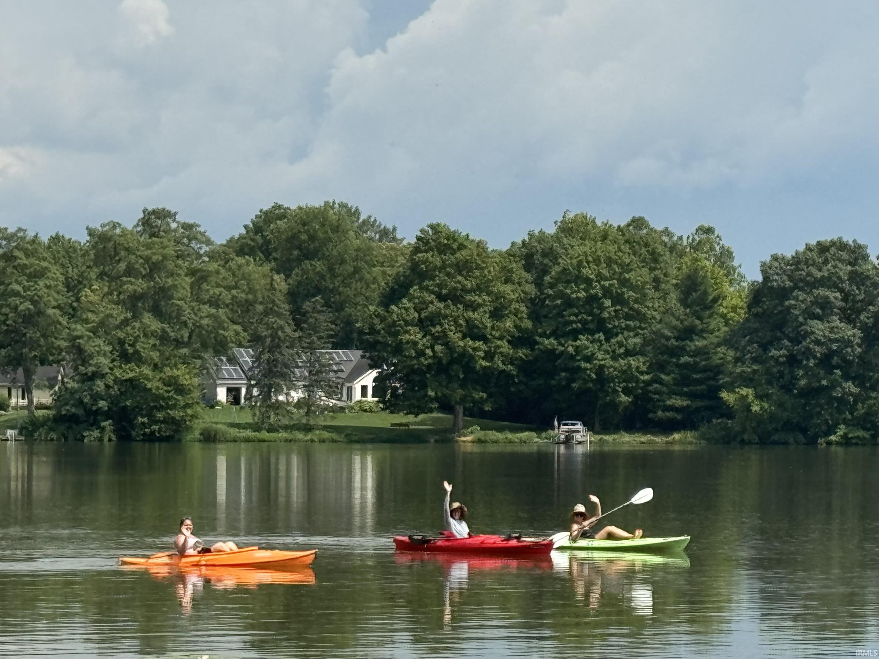 Waterfront property featuring a white exterior, dark roof, and multiple solar panels