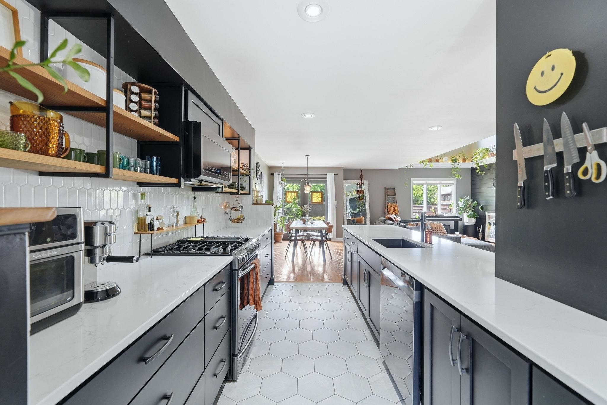 Galley kitchen with white hexagonal tile flooring, black cabinetry, and light-toned countertops