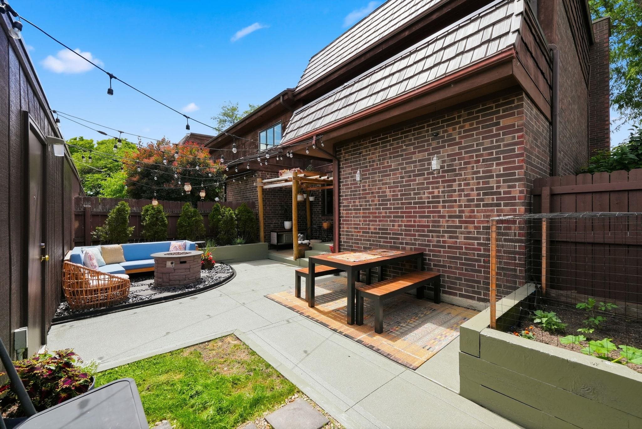 Private outdoor patio featuring a fire pit, dedicated dining area, and a raised garden bed