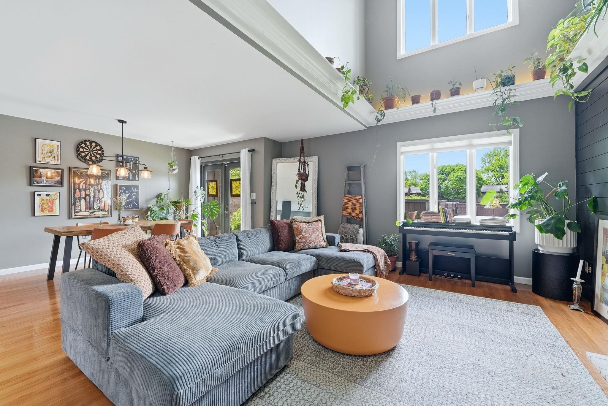 Open-concept living area featuring high ceilings, wood-finish flooring, and ample natural light from multiple windows