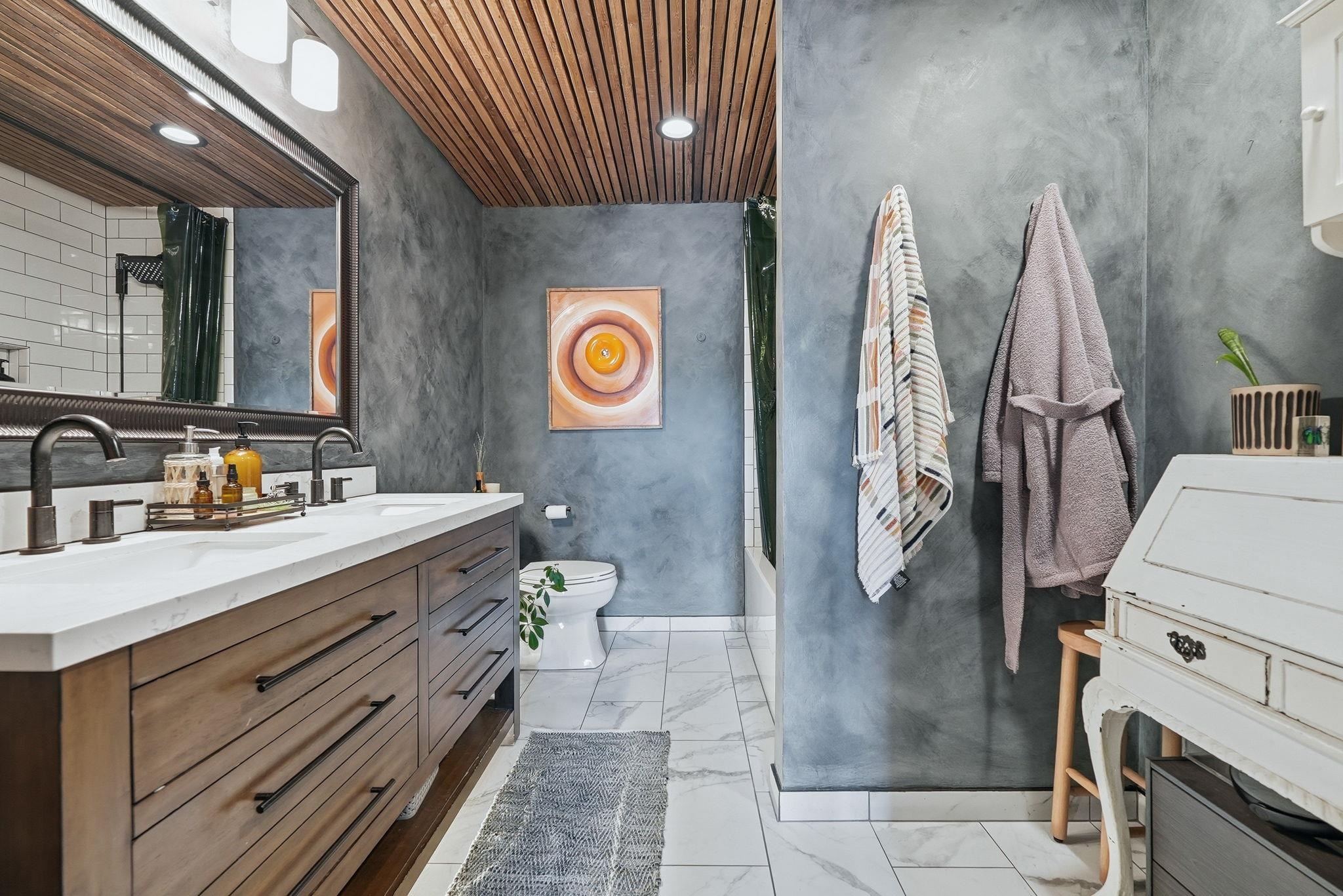 Double vanity featuring a light-toned countertop, wood-finish cabinetry, and matte black fixtures