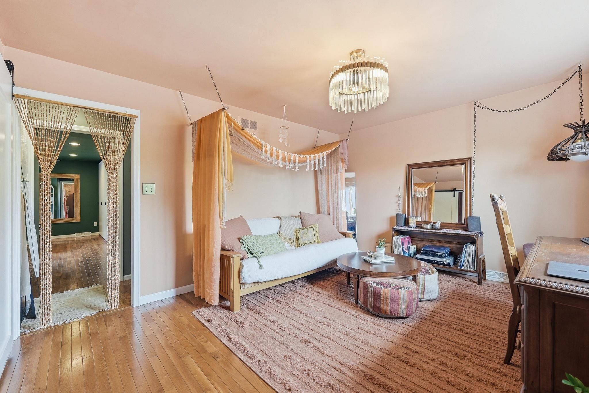 Hardwood-style flooring extends into a room featuring a crystal chandelier and a built-in recessed wall shelf