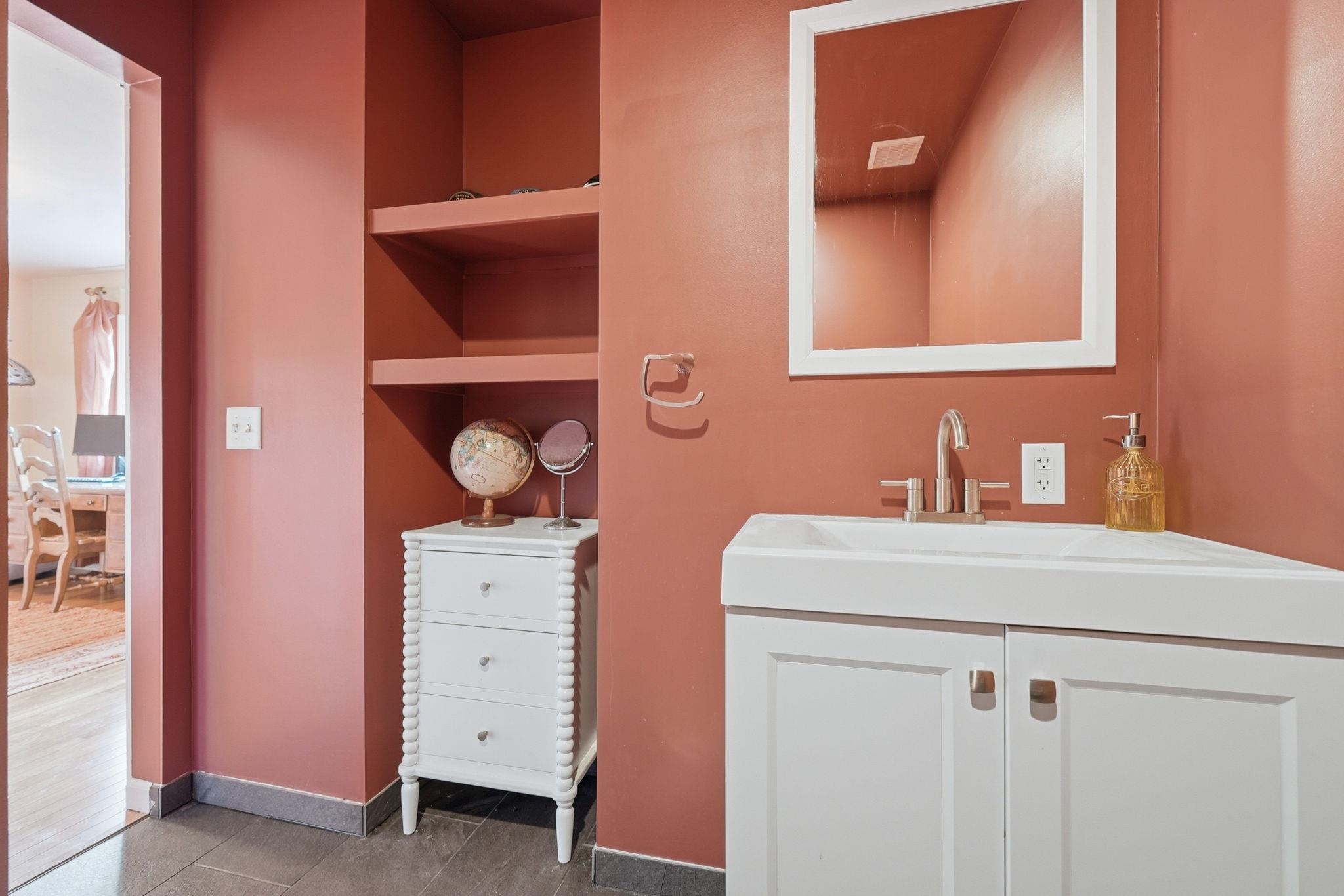 Corner vanity with integrated sink, white shaker-style cabinetry, and brushed nickel faucet
