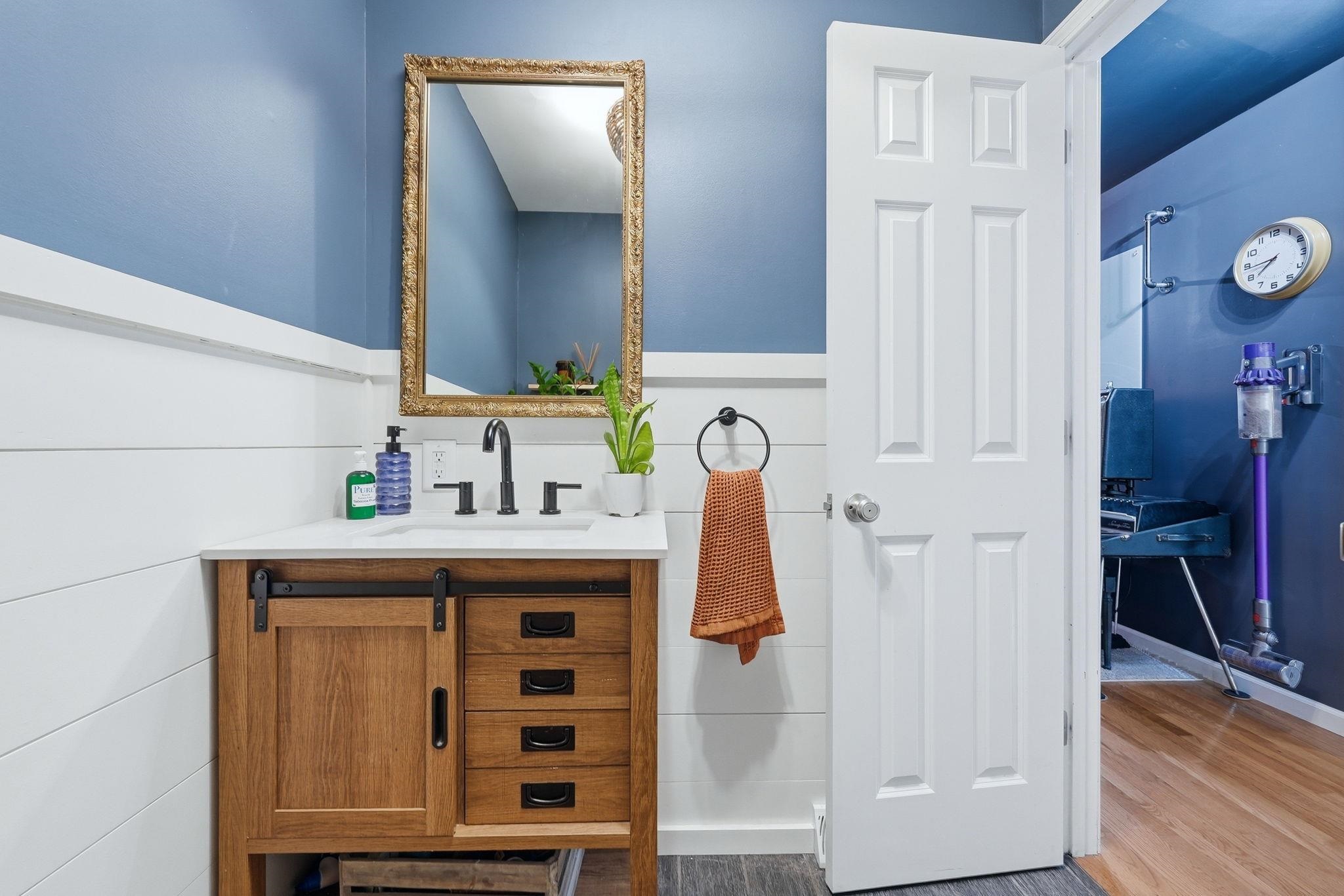 Bathroom featuring a wood-finish vanity with a sliding barn door cabinet and four drawers, a white countertop, and a rectangular undermount sink with a matte black faucet