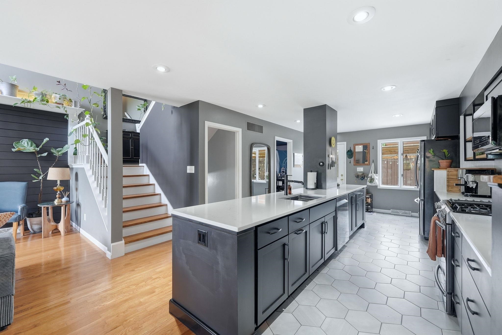 Modern kitchen featuring an expansive center island with a white countertop and dark cabinetry