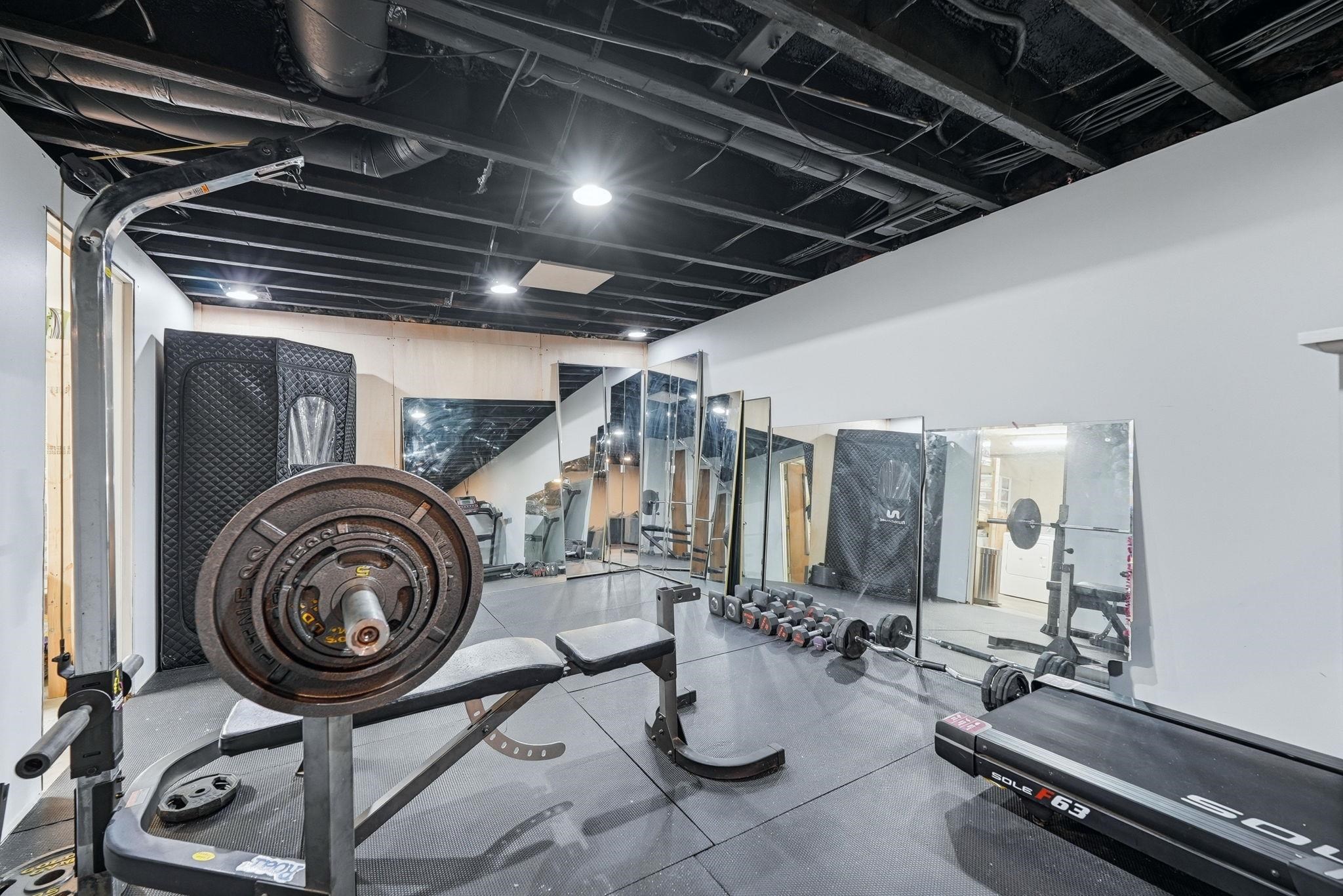 Dedicated fitness space featuring a black painted exposed beam ceiling, recessed lighting, and white walls