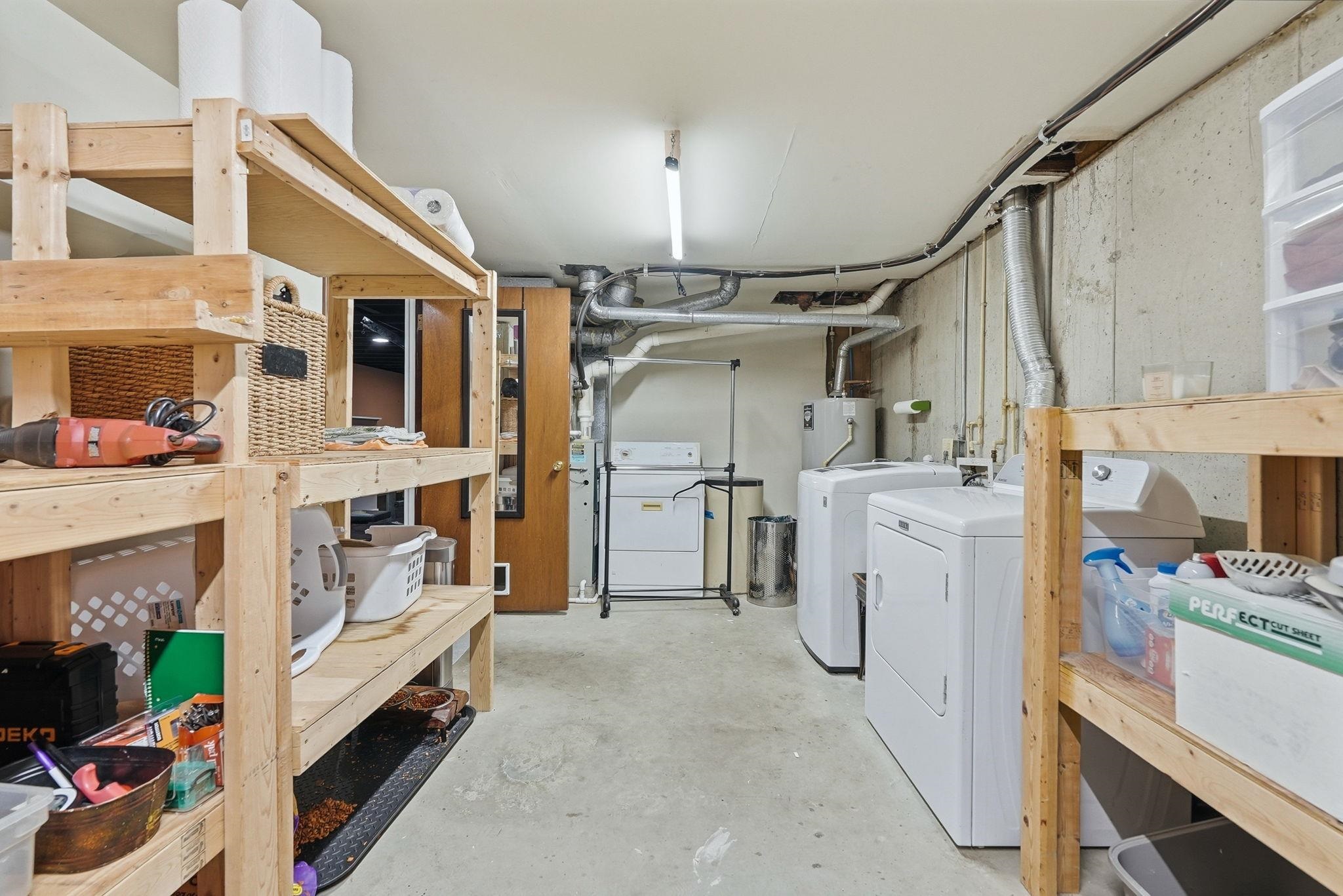 Utility room featuring concrete flooring, exposed concrete walls, and overhead fluorescent lighting