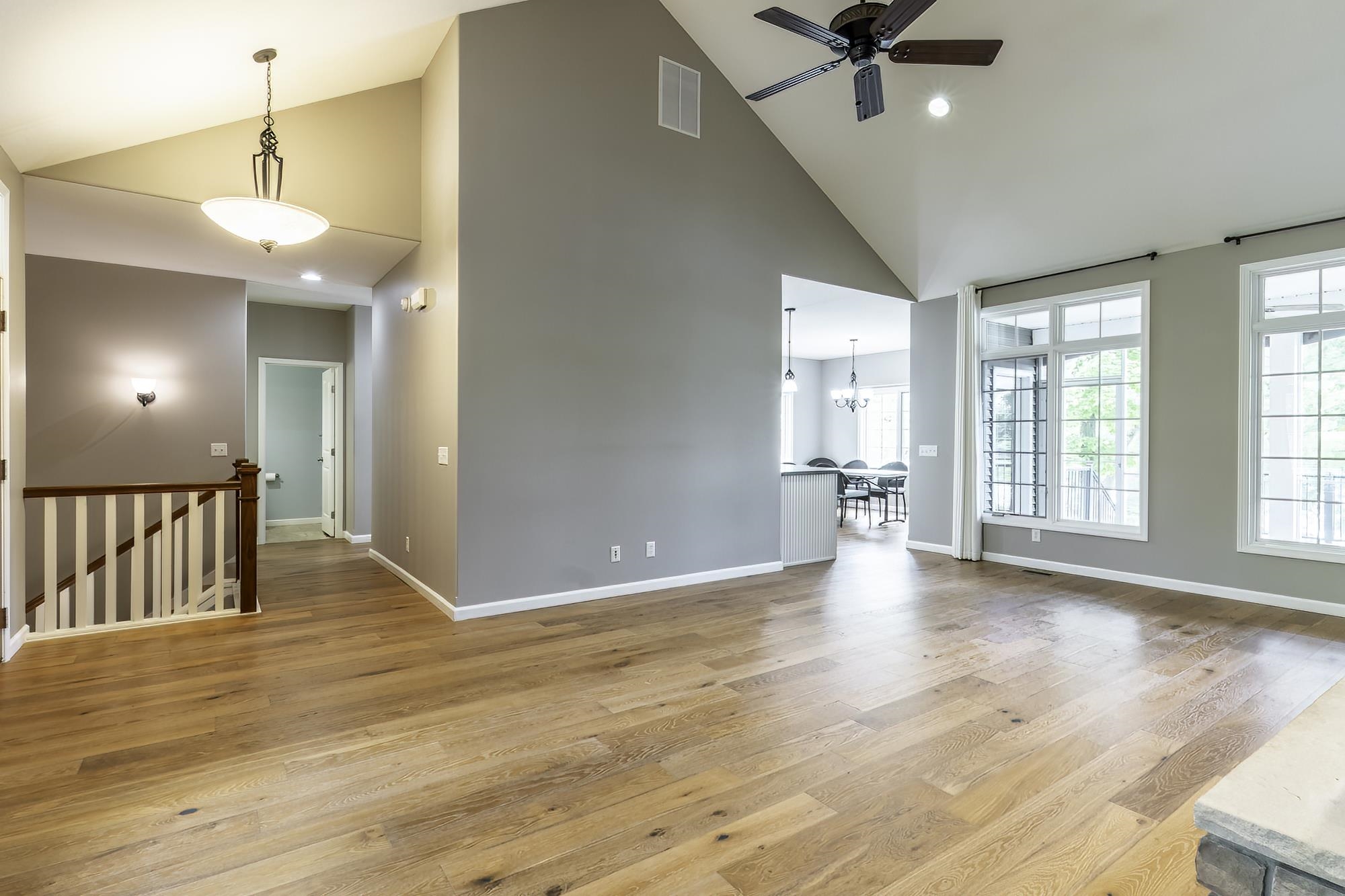 Spacious living area featuring vaulted ceilings, wood-finish flooring, and ample natural light from multiple windows