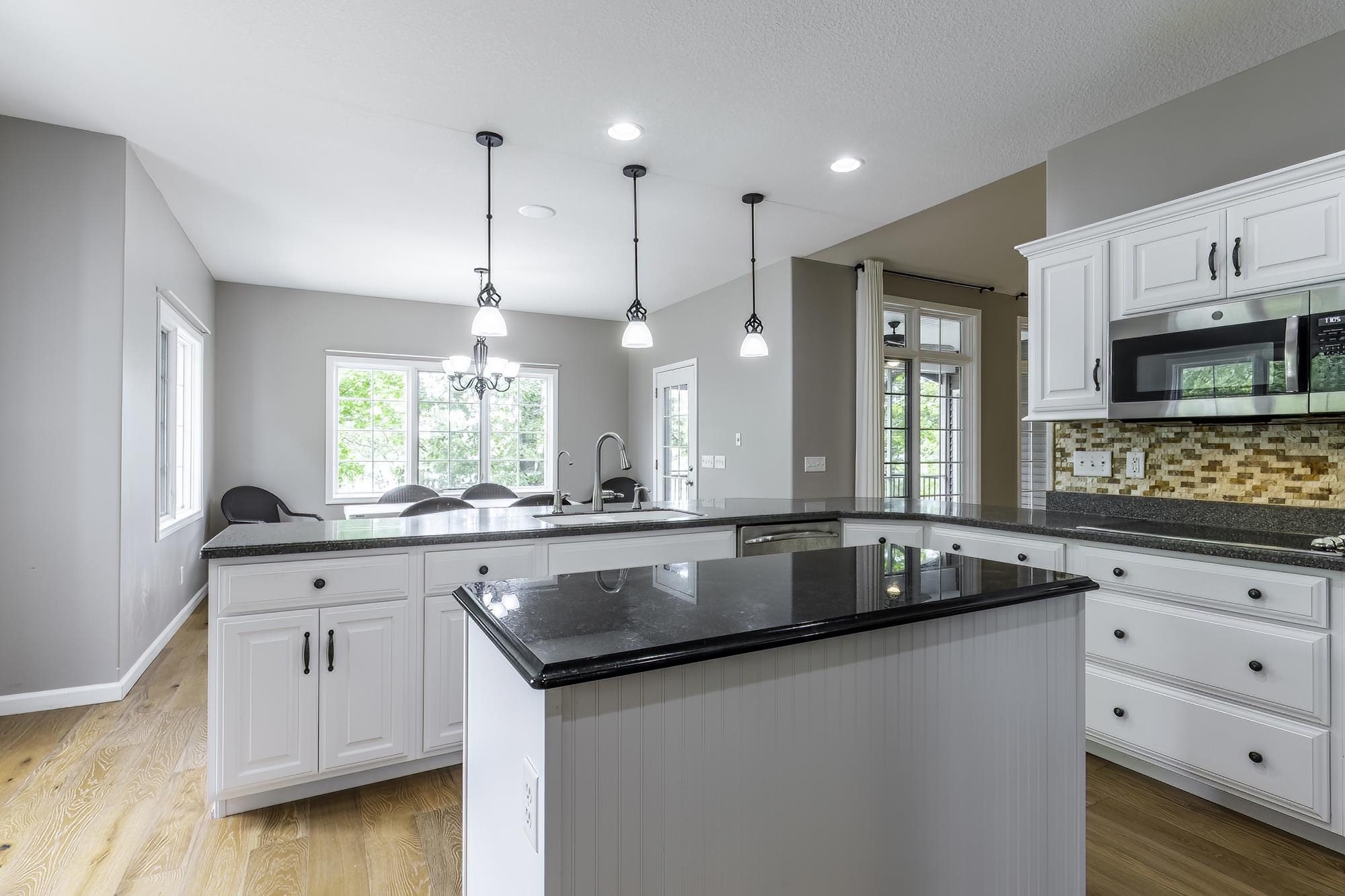 Kitchen featuring white cabinetry with dark hardware, dark countertops, and light wood-finish flooring