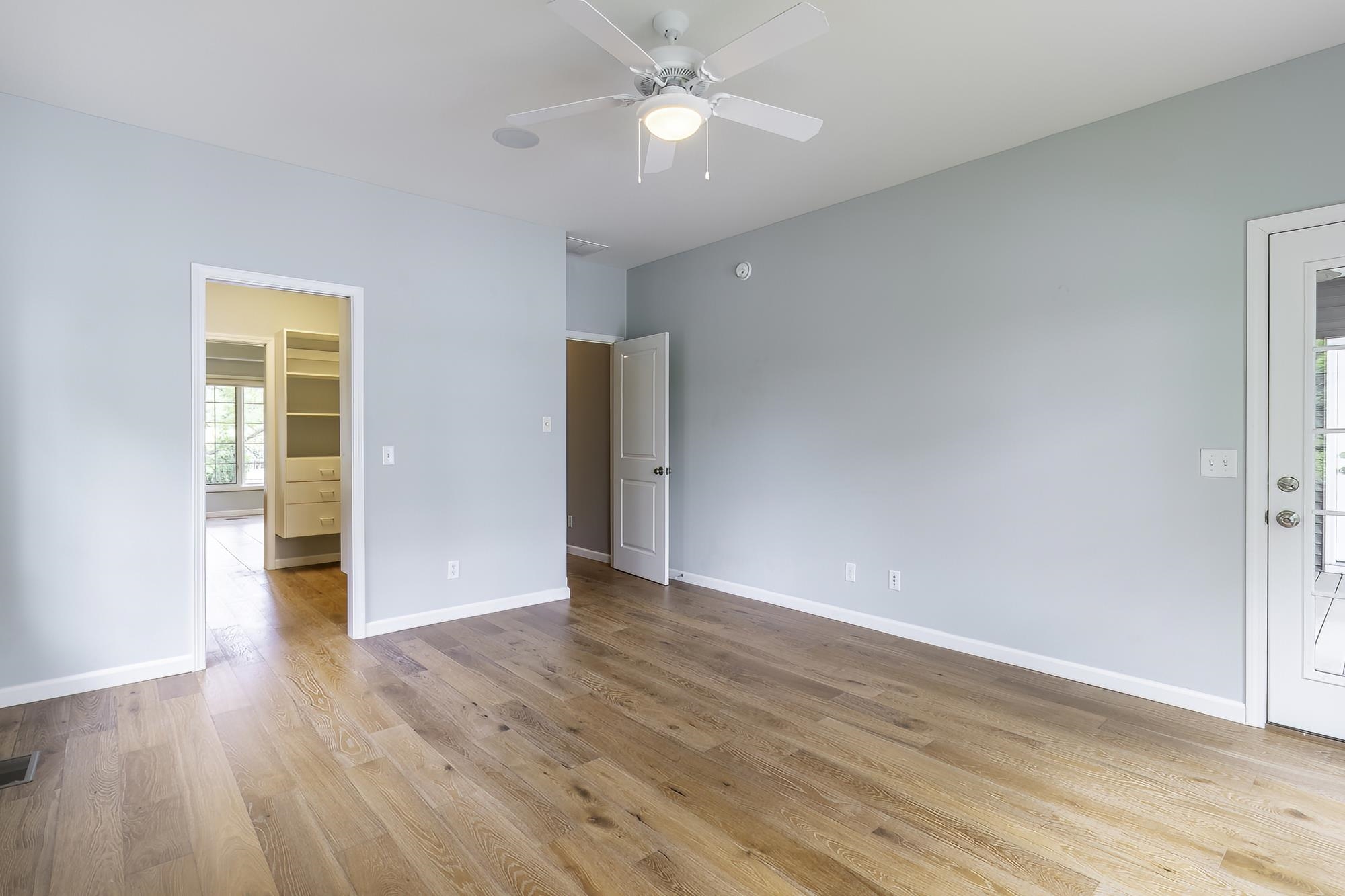 Spacious room with wood-finish flooring, light blue wall paint, and white trim