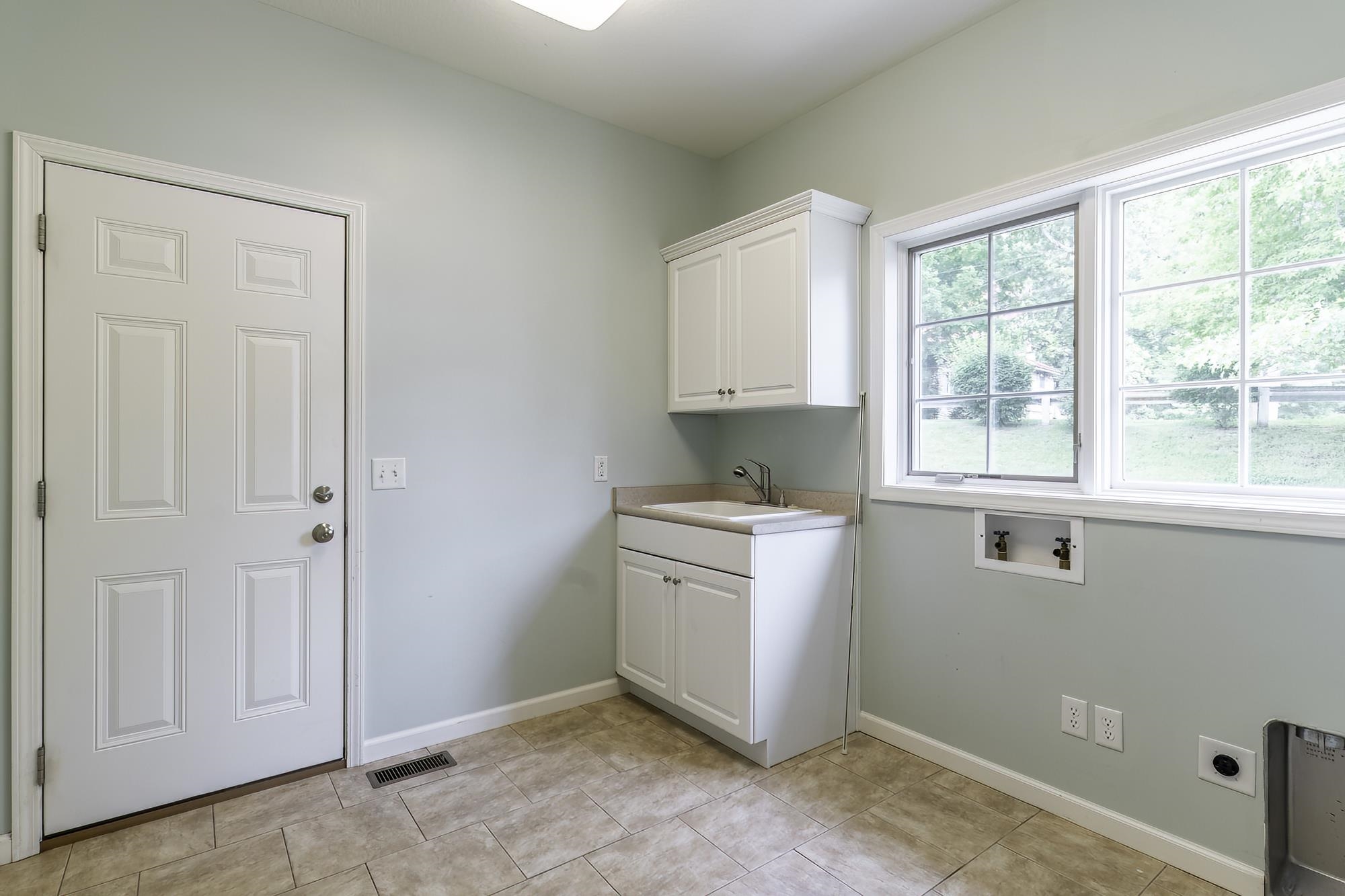 Utility room with light-toned walls, tile flooring, and a white paneled door