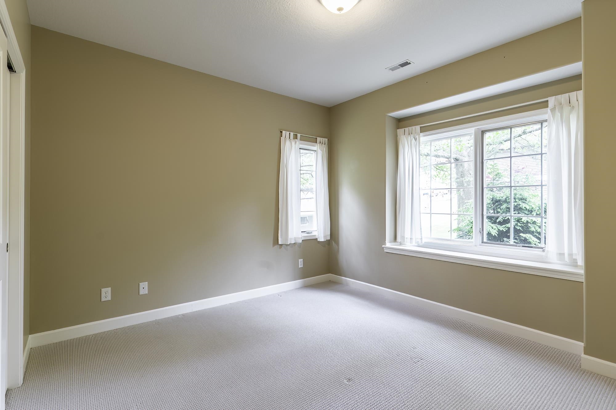 Room featuring neutral wall tones, light-colored carpet, white baseboards, and two windows