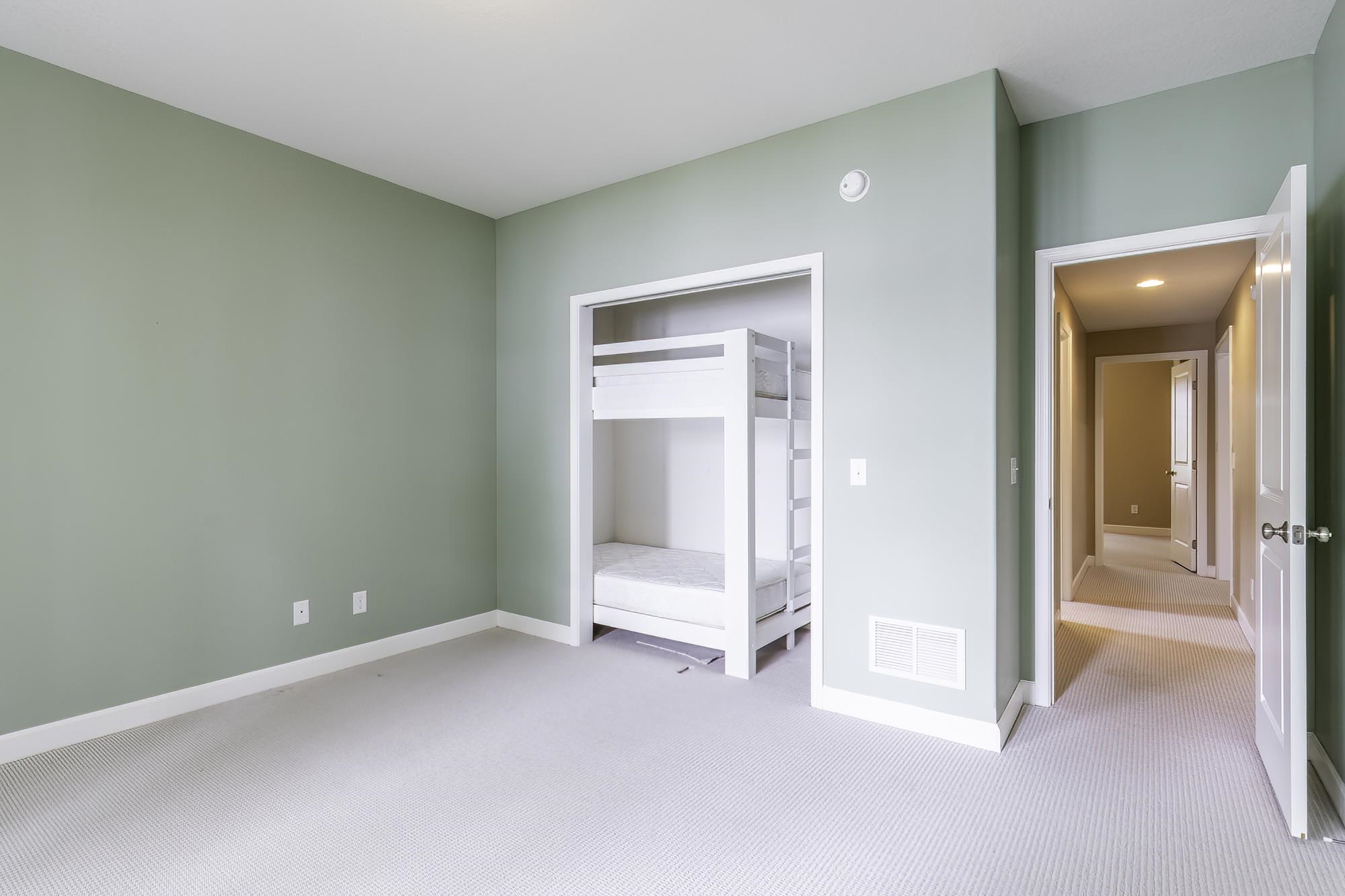 Neutral tone wall paint, light-colored carpeting, white trim, and a built-in bunk bed structure within an alcove