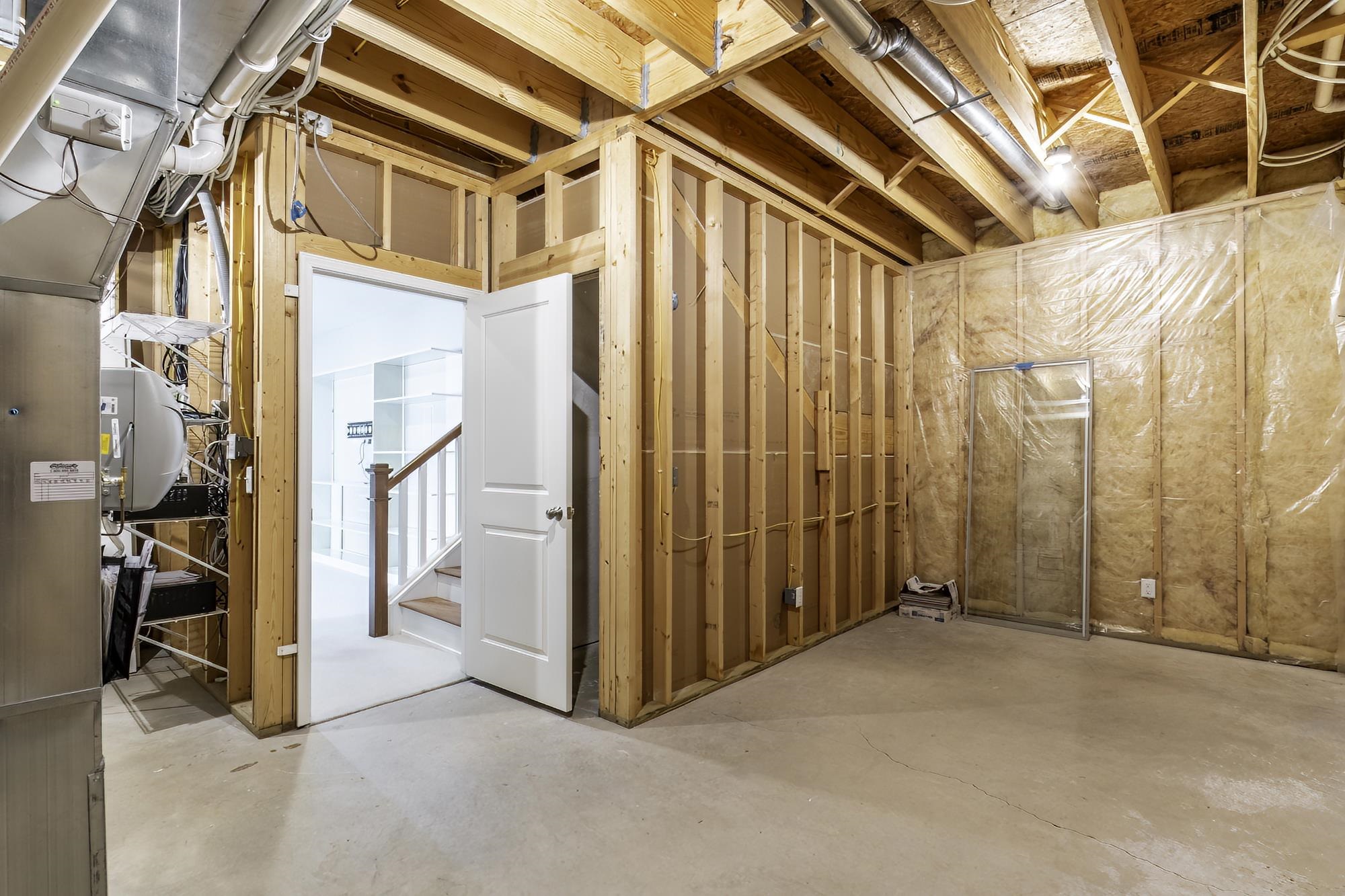 Unfinished basement area featuring exposed wood framing, concrete flooring, and visible ductwork