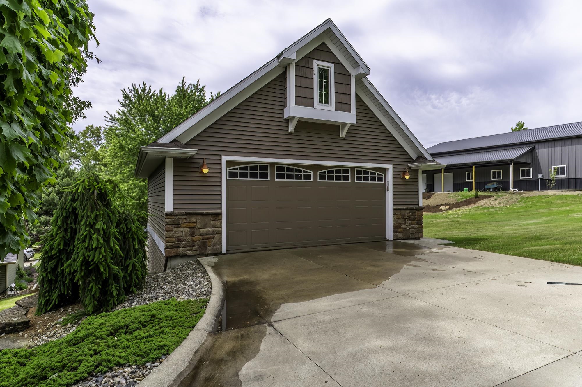 Attached garage featuring horizontal siding and stone veneer accents