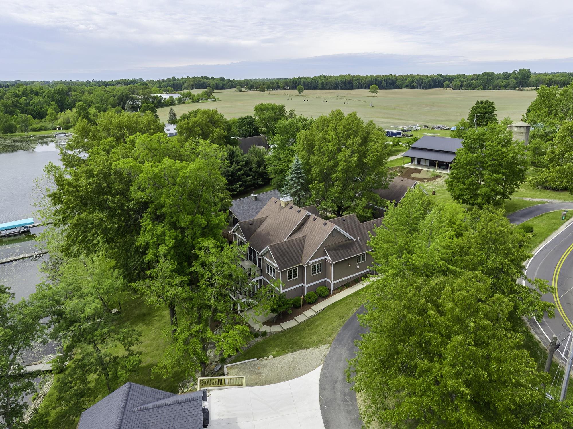 Waterfront property with a multi-story residence featuring a brown siding exterior, multi-pitch roof, and a private dock on the water