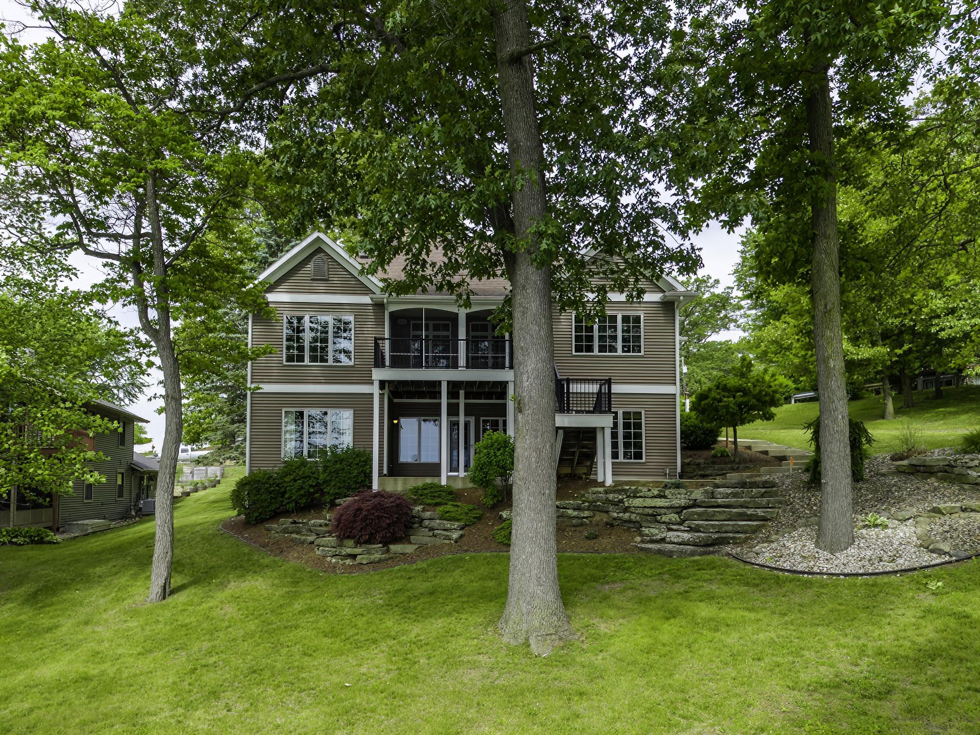 Multi-level residence featuring a screened porch and an open-air balcony with black railings