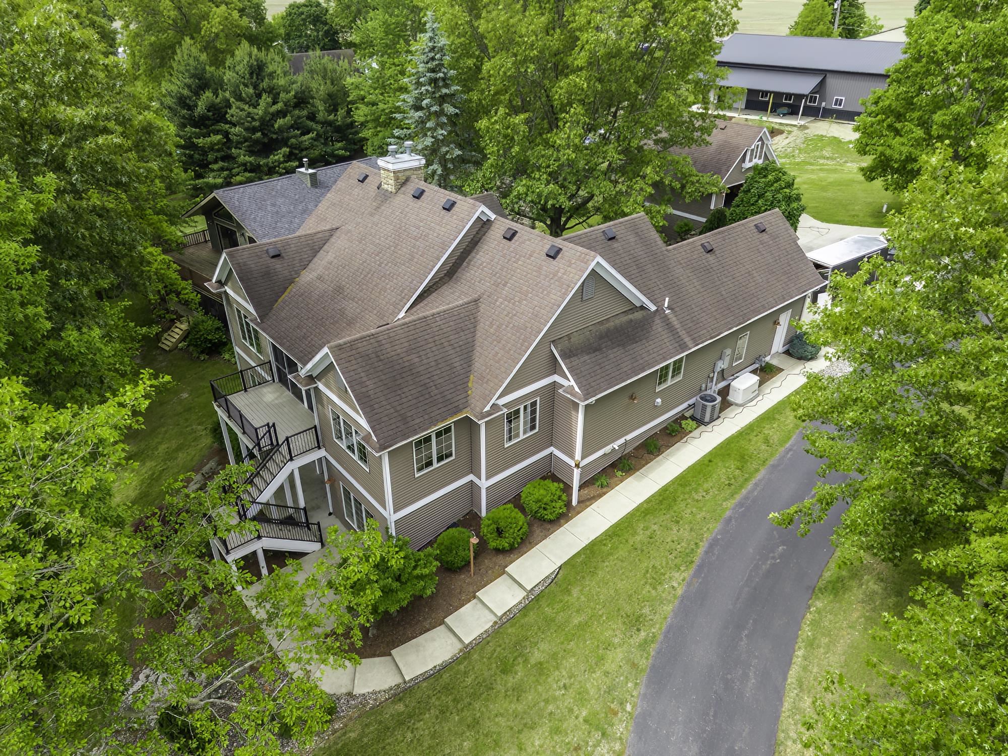 Multi-level residence featuring a brown shingle roof and neutral-toned siding