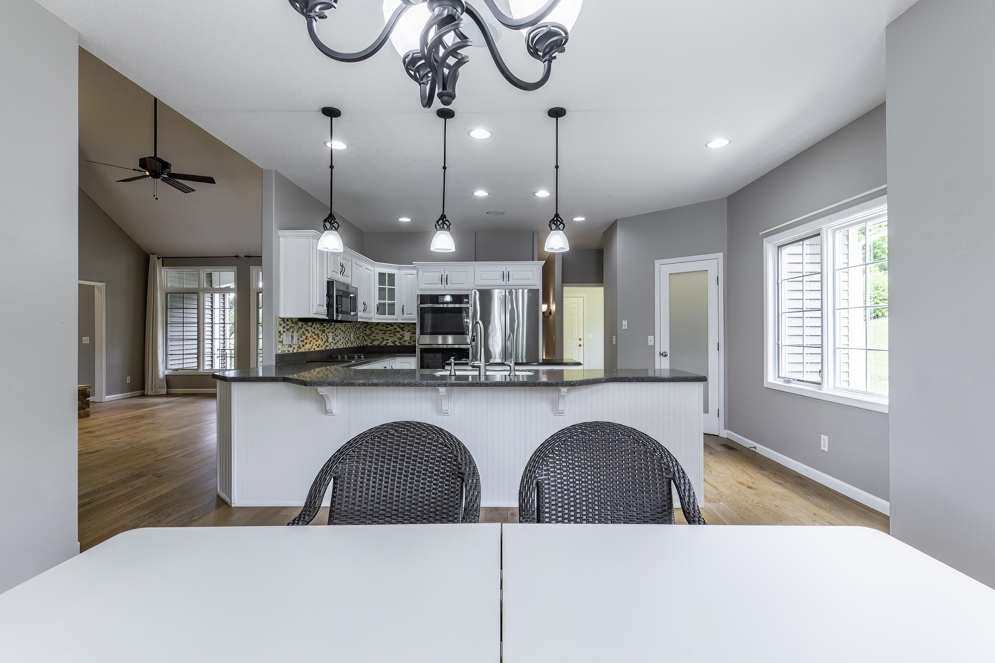 Kitchen featuring white cabinetry, built-in stainless steel appliances, dark countertops, and a mosaic tile backsplash