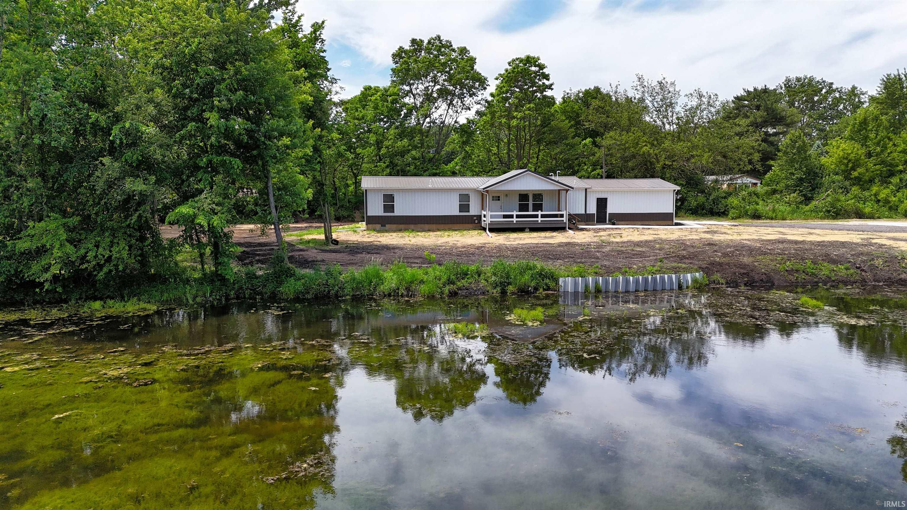 Waterfront property featuring a single-story residence with a white and brown exterior