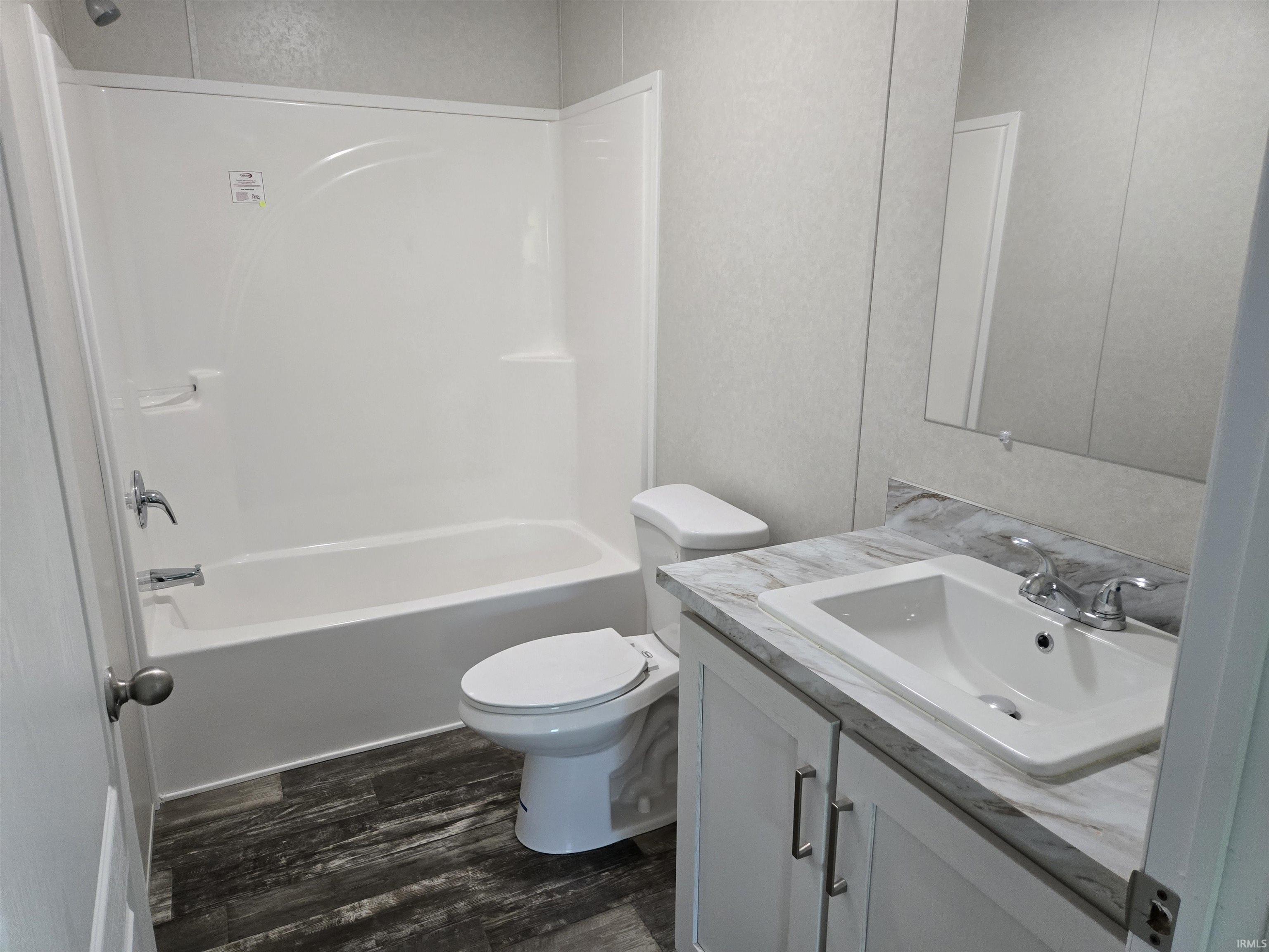 Bathroom featuring a full tub and shower combination, a white vanity with an integrated sink, a spacious countertop, and wood-finish flooring