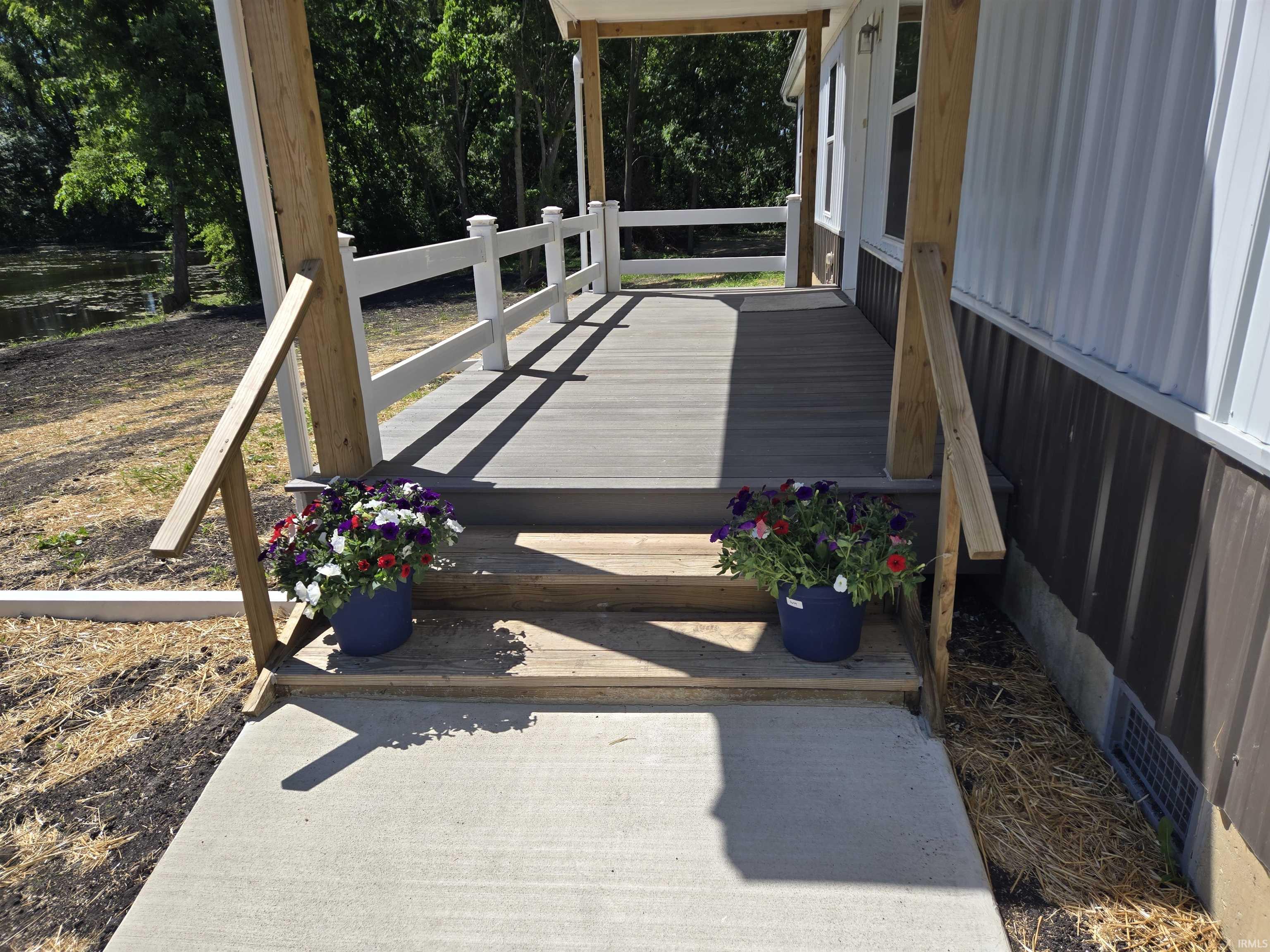 Front porch featuring composite decking, white railing, and natural wood posts