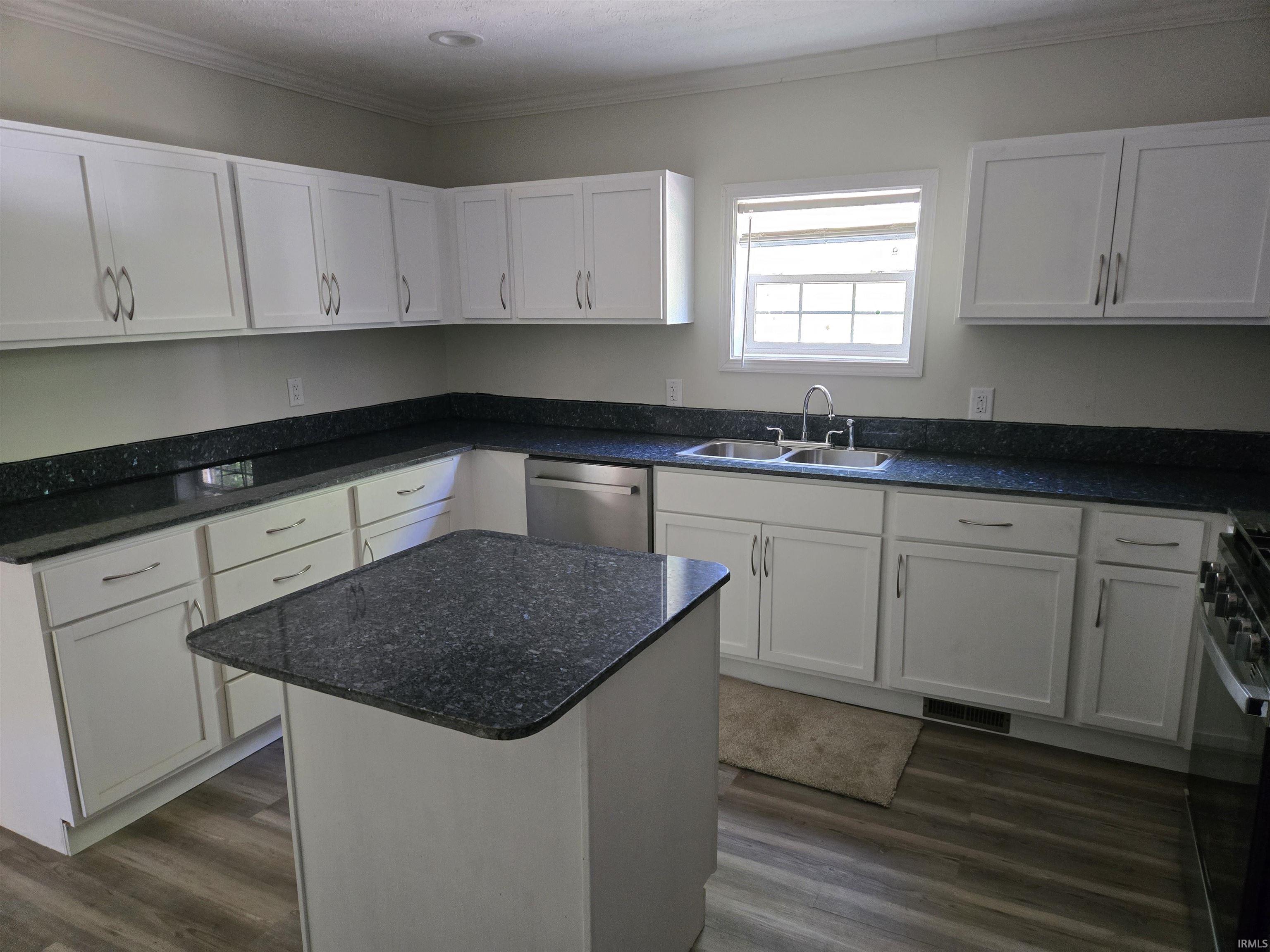Kitchen featuring white shaker-style cabinetry, dark speckled countertops, and wood-finish flooring