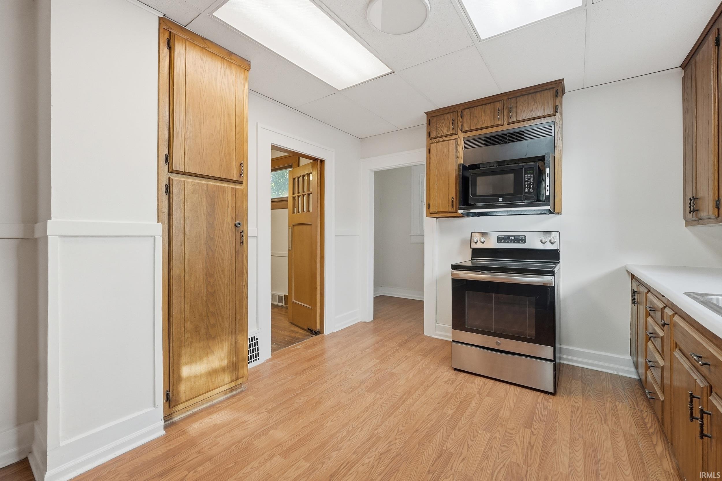 Kitchen featuring wood-finish flooring, white walls, and wood cabinetry