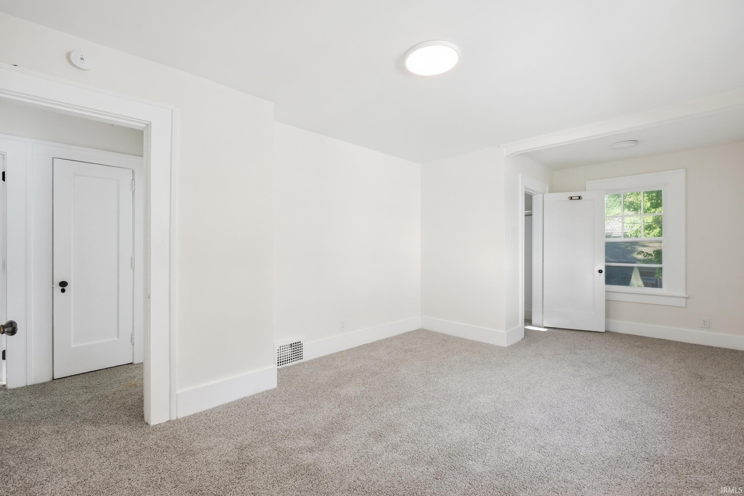 Carpeted room with a ceiling-mounted light fixture, white walls, and white trim