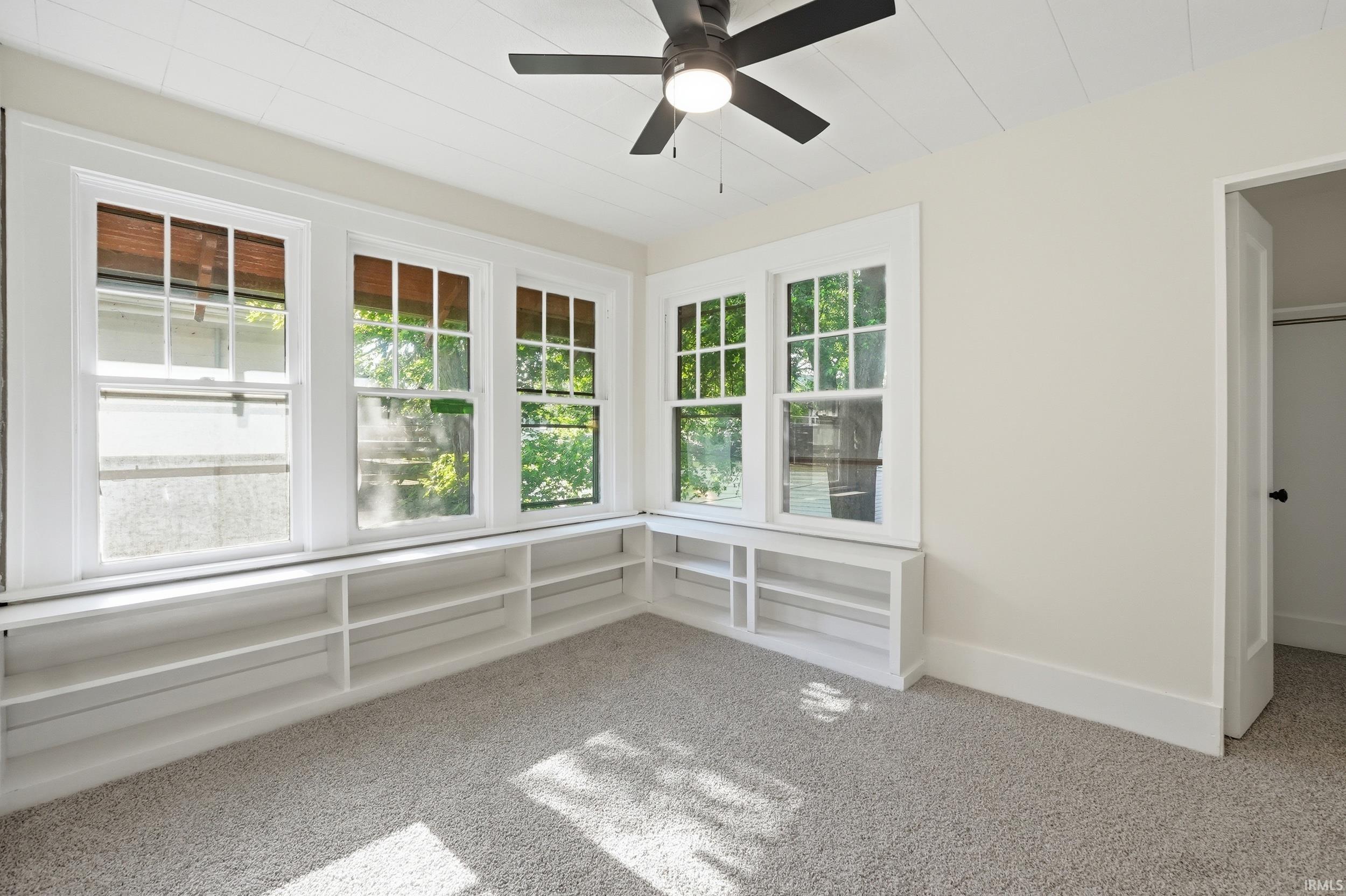 Room featuring a corner window bench with integrated open shelving