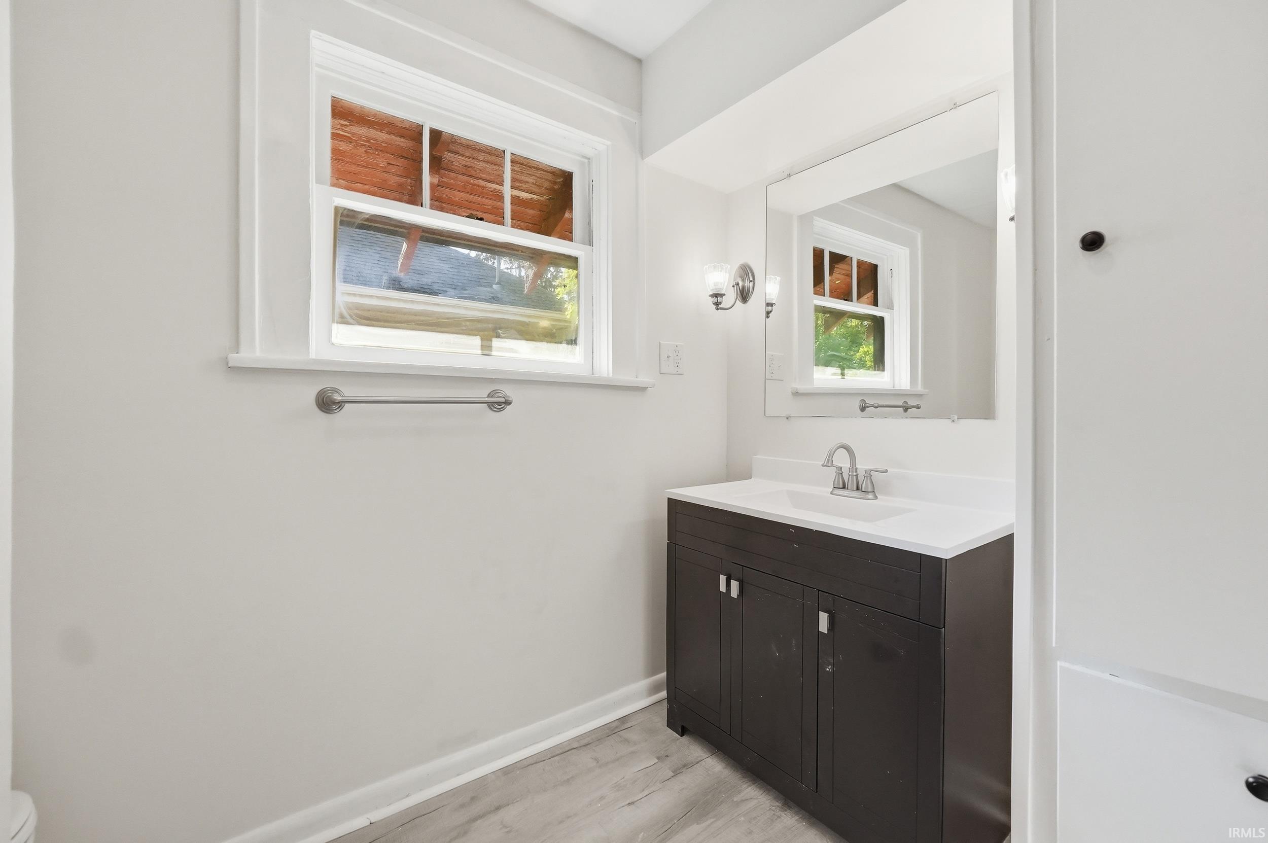 Bathroom with a dark wood-finish vanity, white countertop with integrated sink, and a large mirror