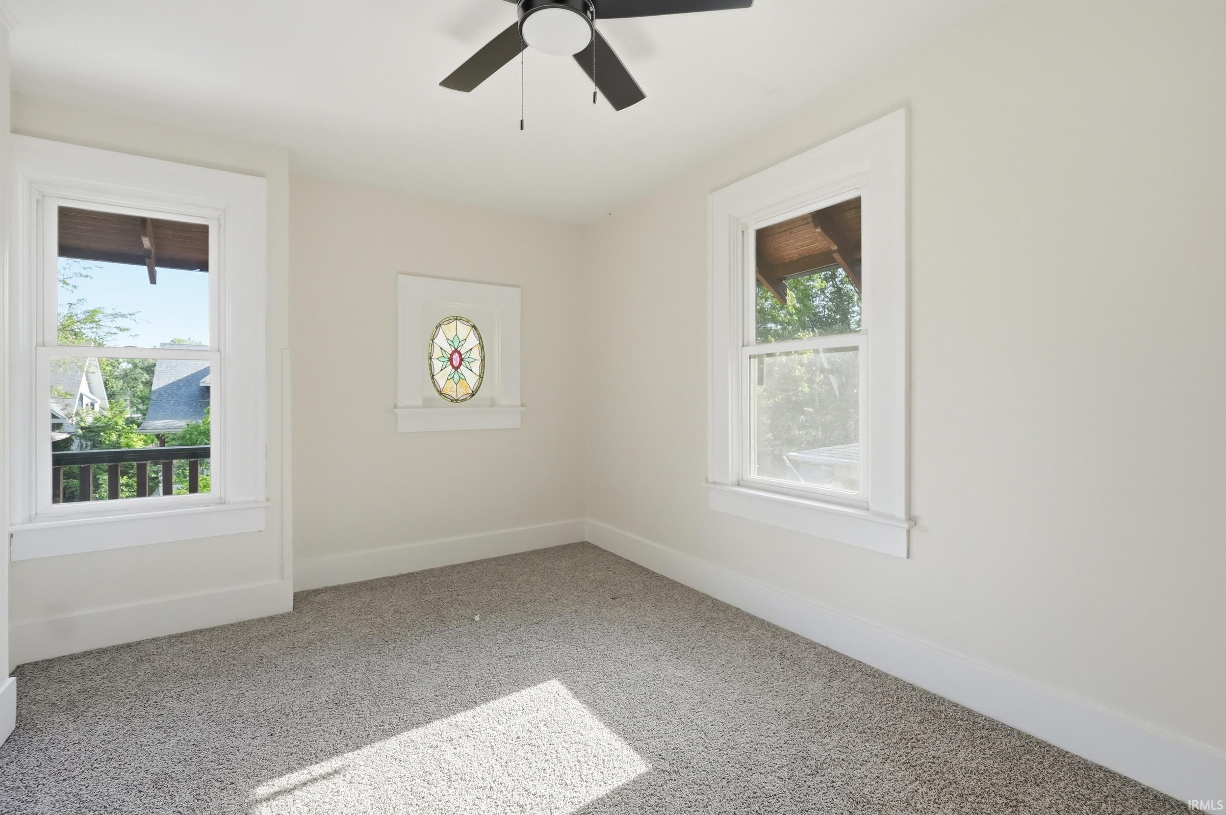 Room featuring light-toned carpeting, white walls, and a ceiling fan