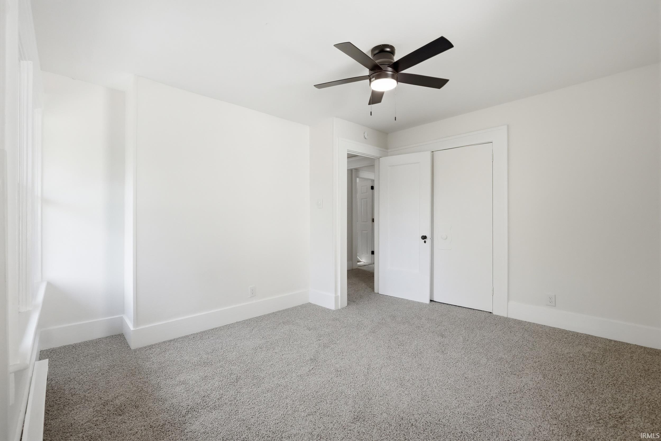 Spacious room featuring light gray carpet flooring, white walls, and bright white trim