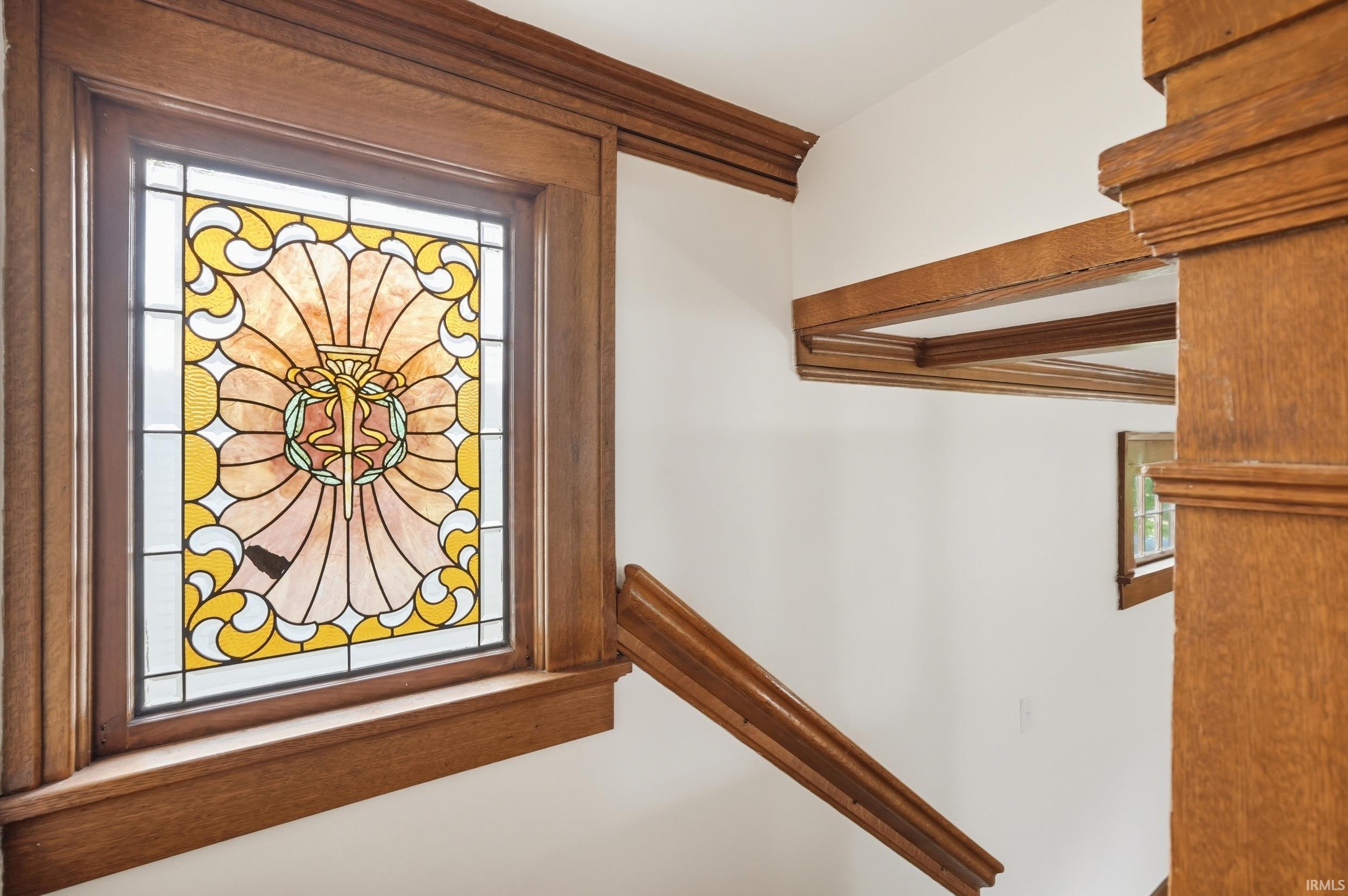 Stained glass window with intricate design, framed by rich wood millwork