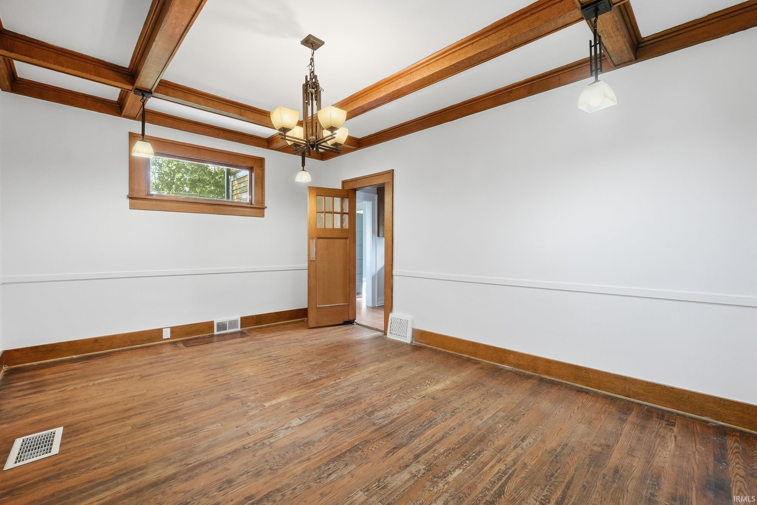 Room with wood-finish flooring, white walls, and a white ceiling featuring exposed wood beams