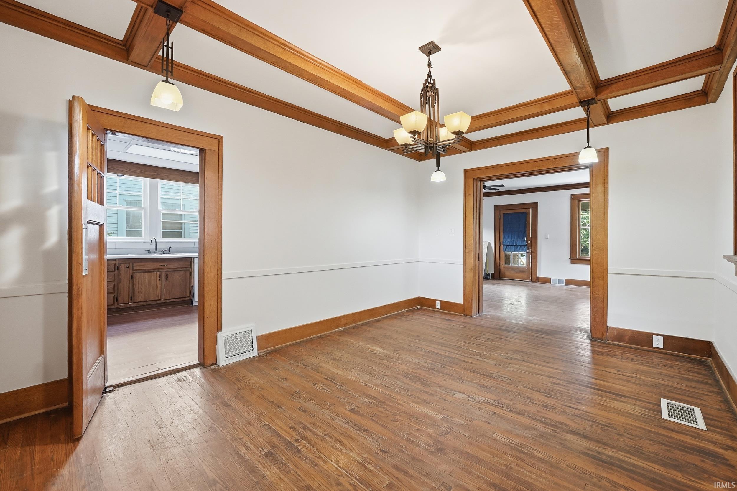 Hardwood flooring throughout, complemented by white walls and a coffered ceiling